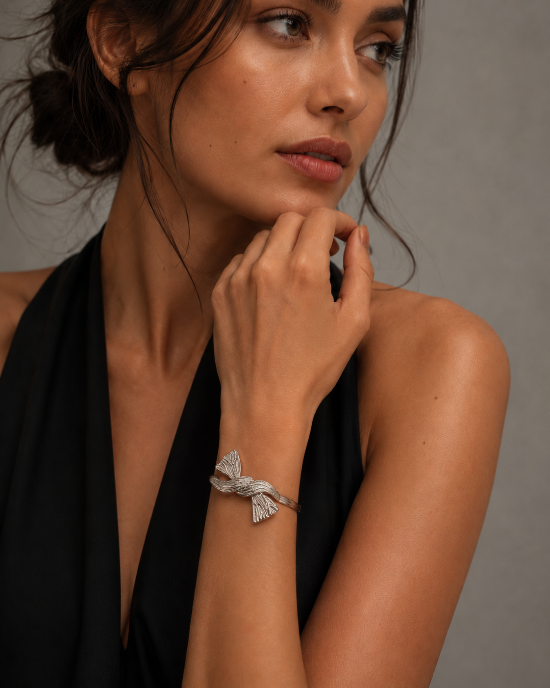 Silver Textured Ribbon Bow Cuff Bracelet worn on wrist with black halter
