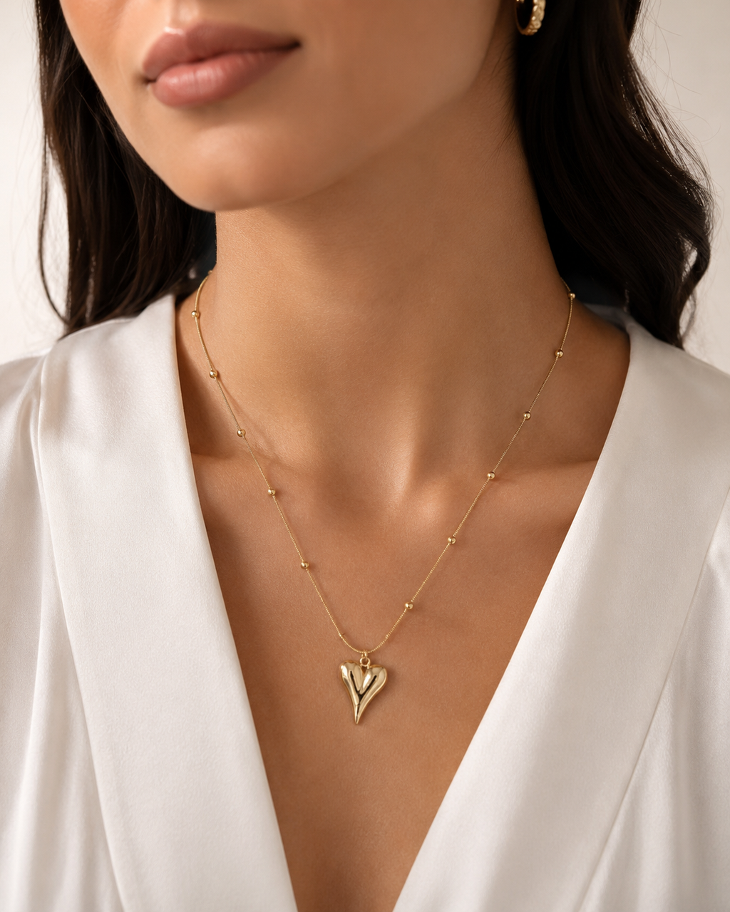Gold Puffy 3D Heart Pendant Satellite Chain Necklace worn on model with white silk deep V-neck top