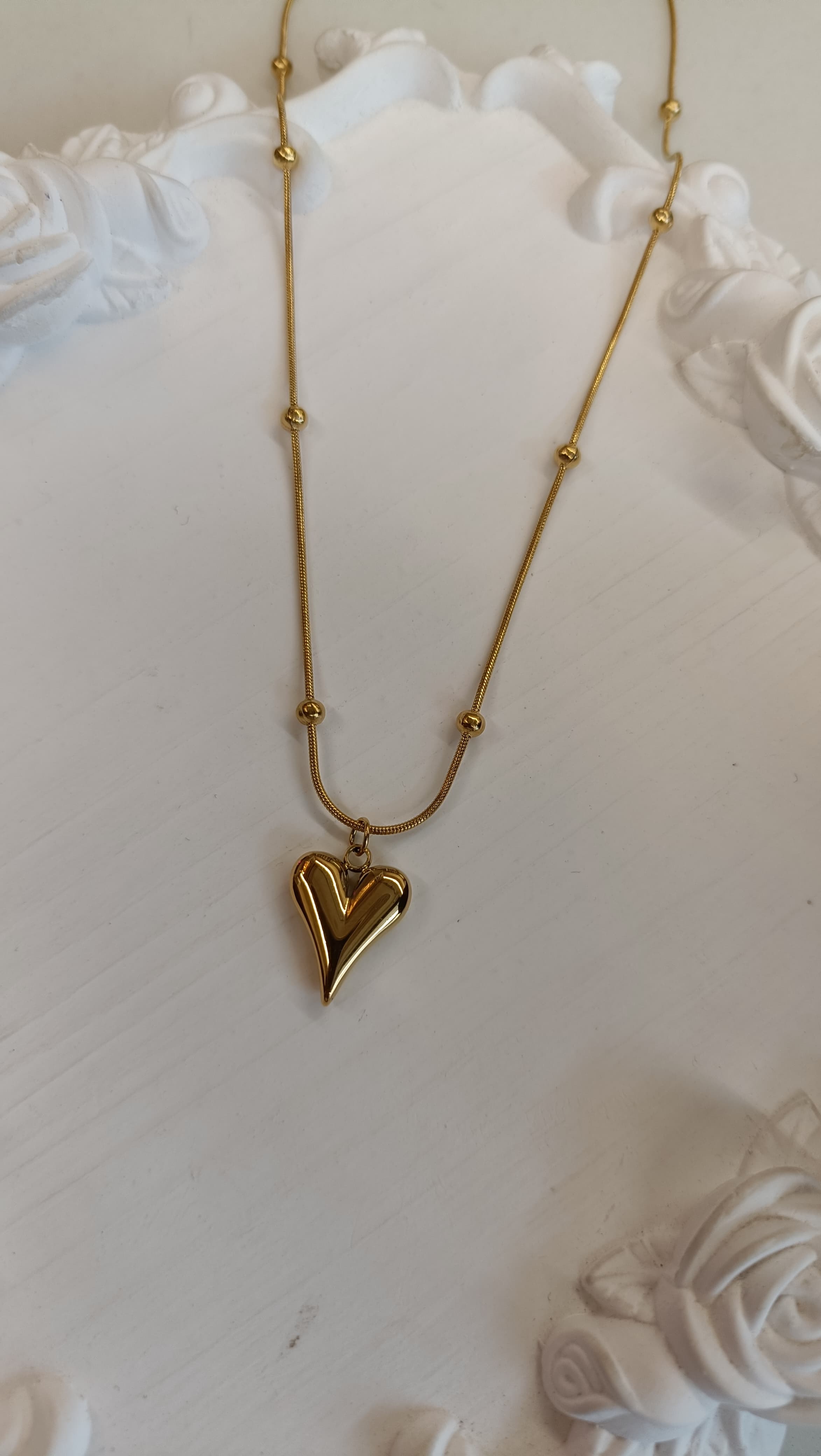 Gold Puffy 3D Heart Pendant Satellite Chain Necklace full length flat lay on white surface with white roses showing heart pendant detail
