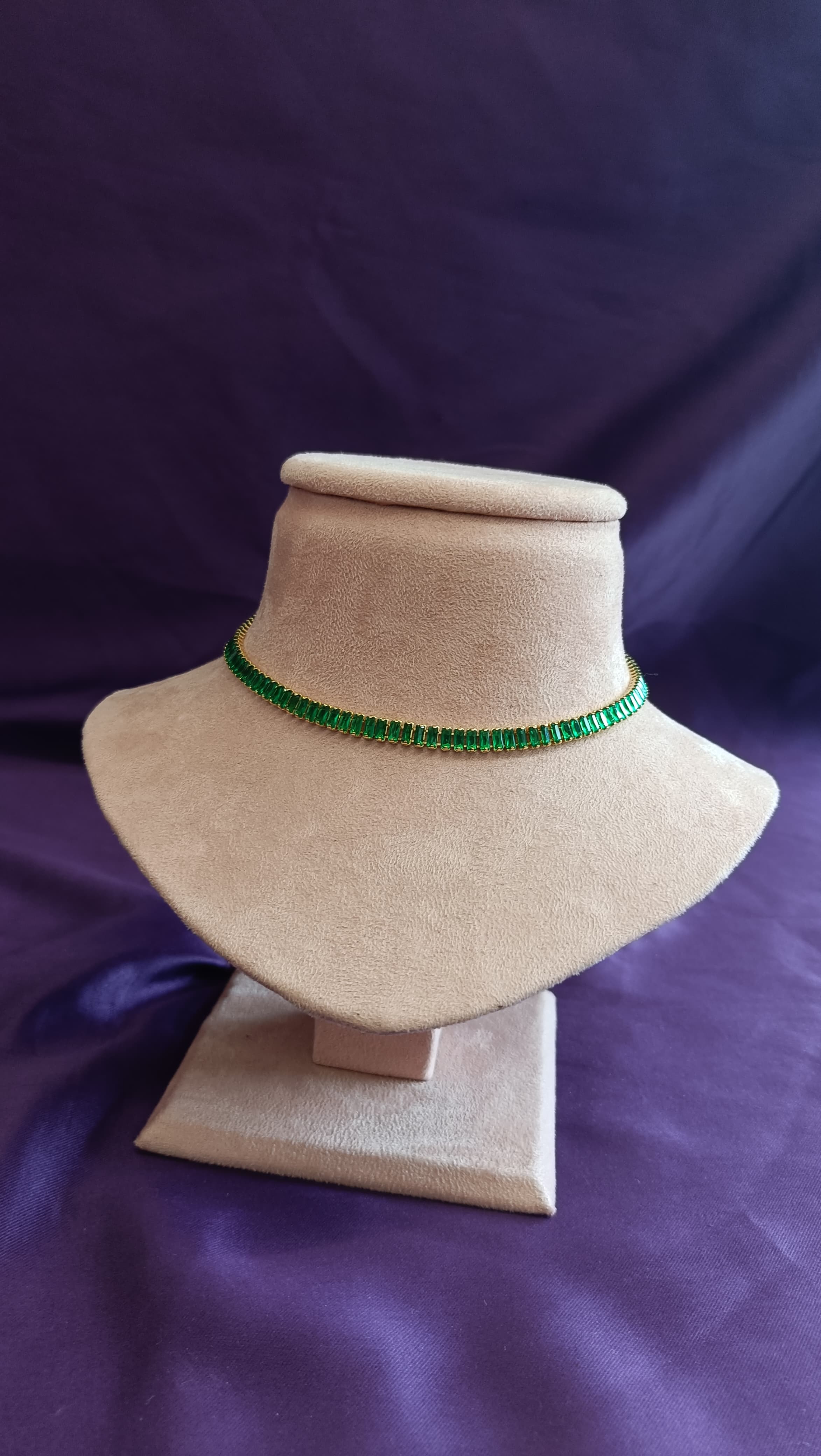 Gold Emerald Baguette Crystal Tennis Choker Necklace on beige velvet bust display against purple fabric background
