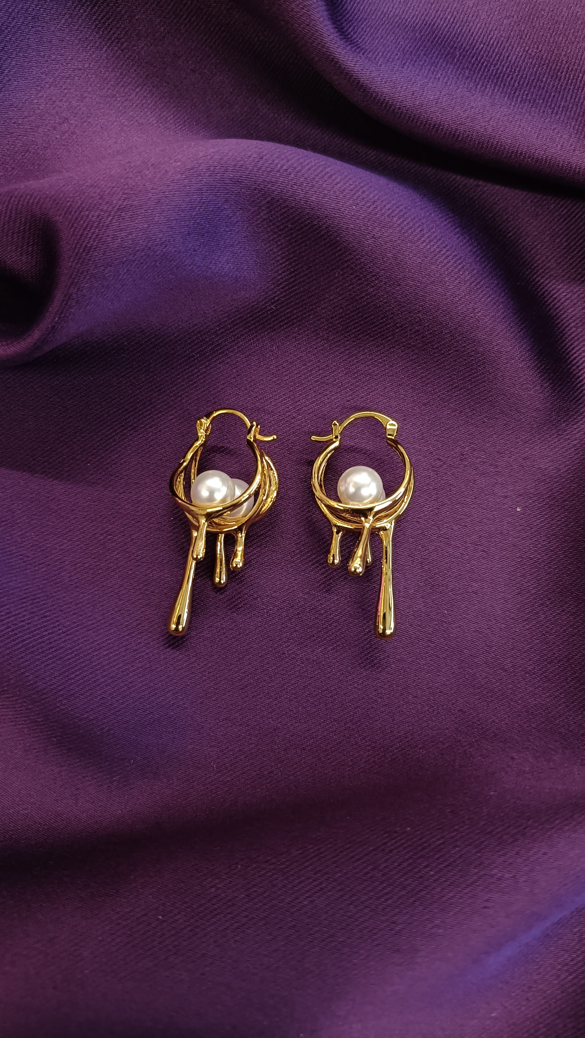 Gold Molten Drip Pearl Hoop Earrings flat lay pair on purple fabric