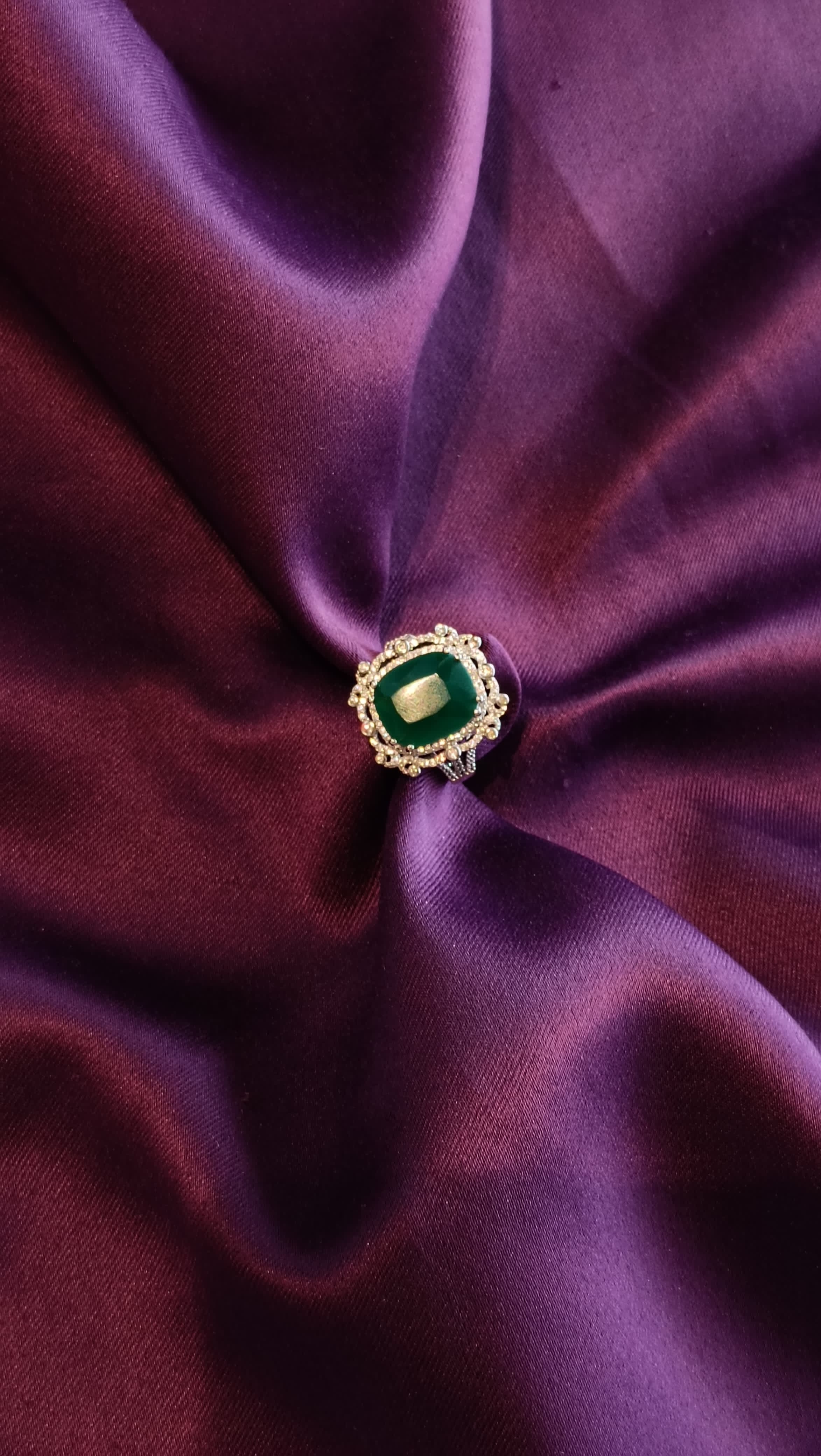 Gold Emerald Green Cushion Halo Cocktail Ring top view on purple fabric