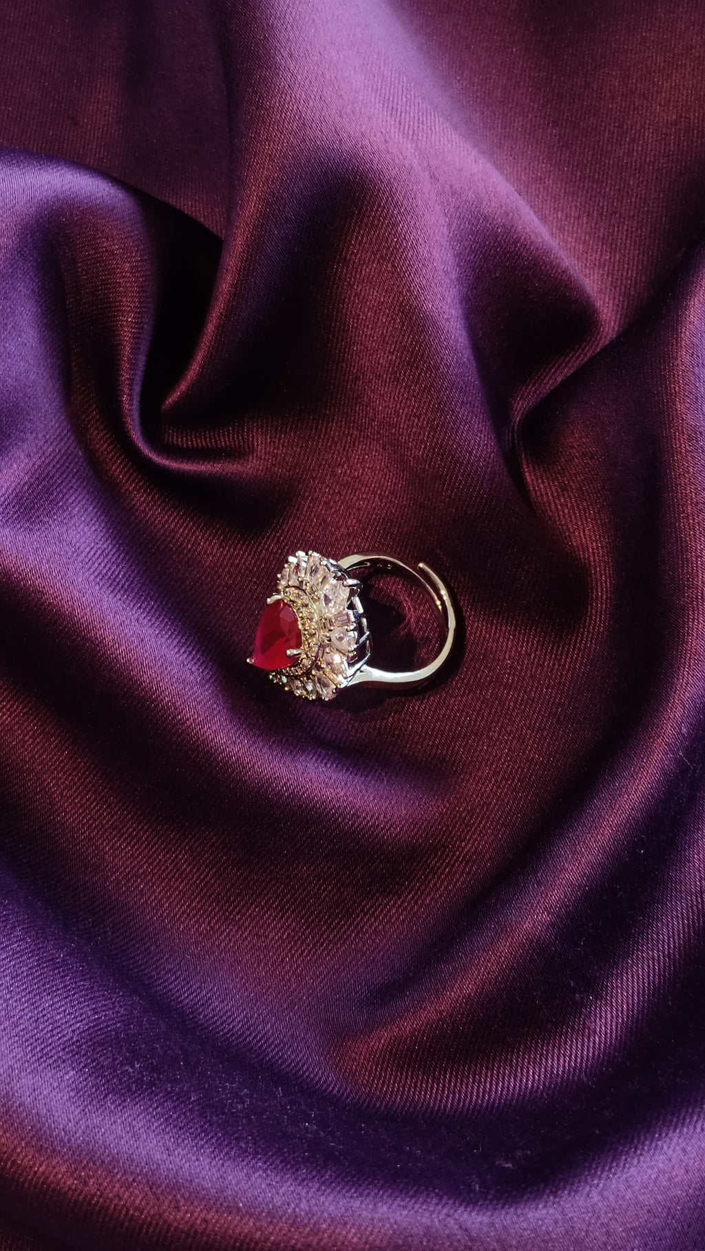 Silver Ruby Red Pear-Cut Sunburst Halo Ring side view on purple fabric