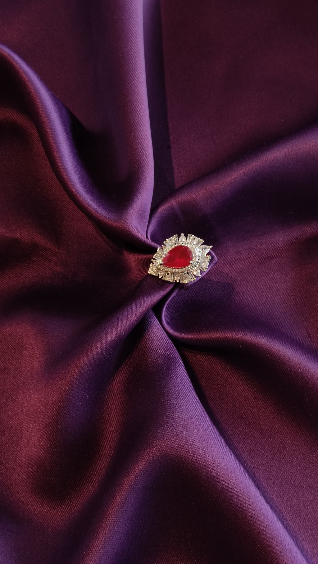 Silver Ruby Red Pear-Cut Sunburst Halo Ring top view on purple fabric