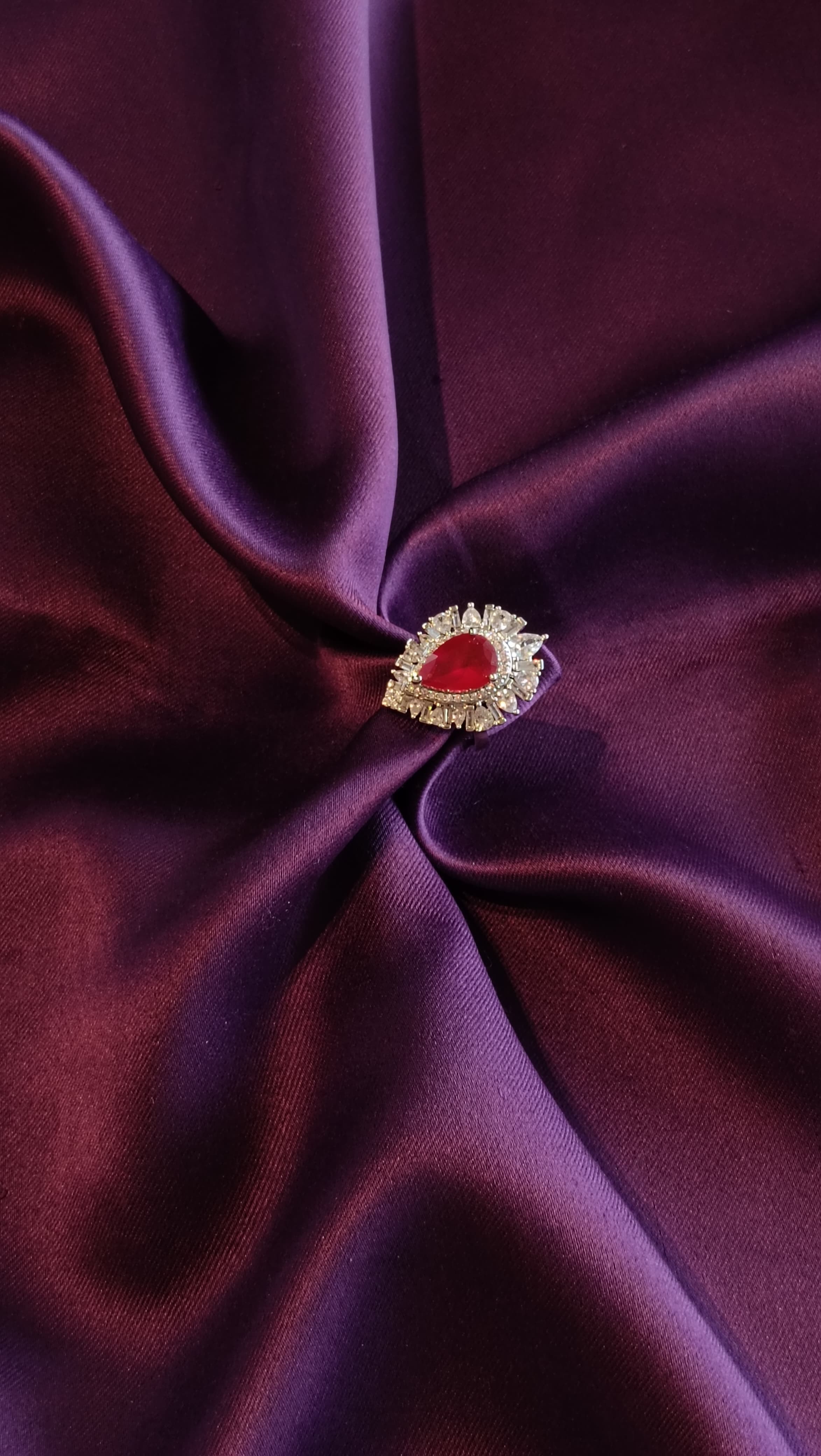 Silver Ruby Red Pear-Cut Sunburst Halo Ring top view on purple fabric