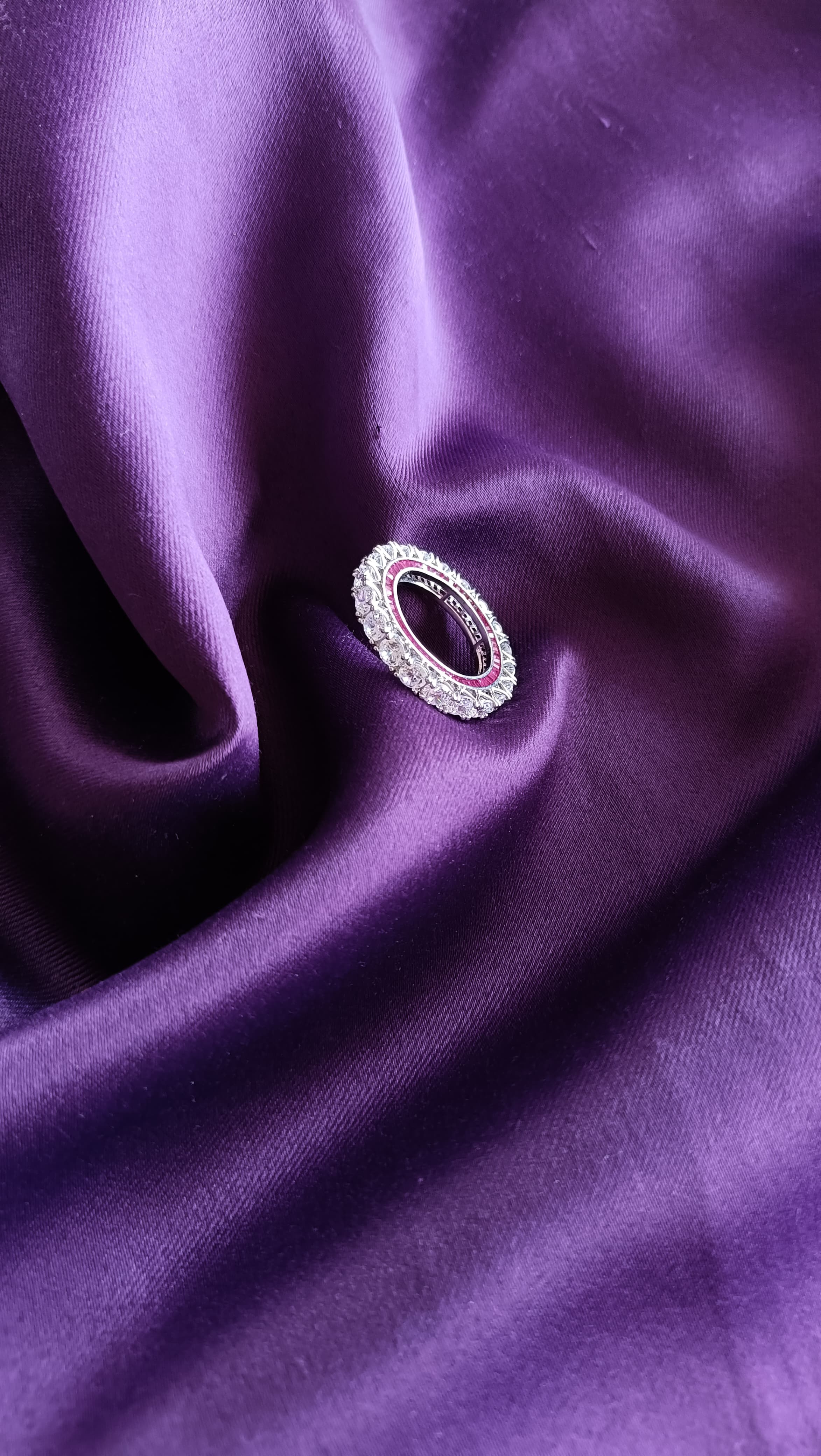 Diamond Eternity Band with Ruby Accent on purple fabric close-up