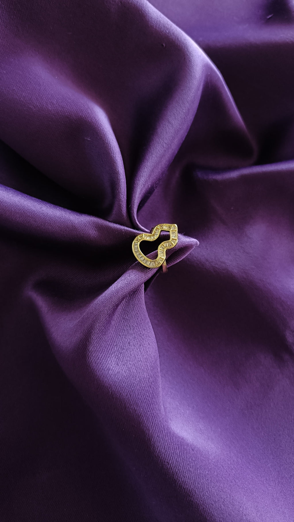 Gold Open Wave Baguette Ring flat lay on purple fabric