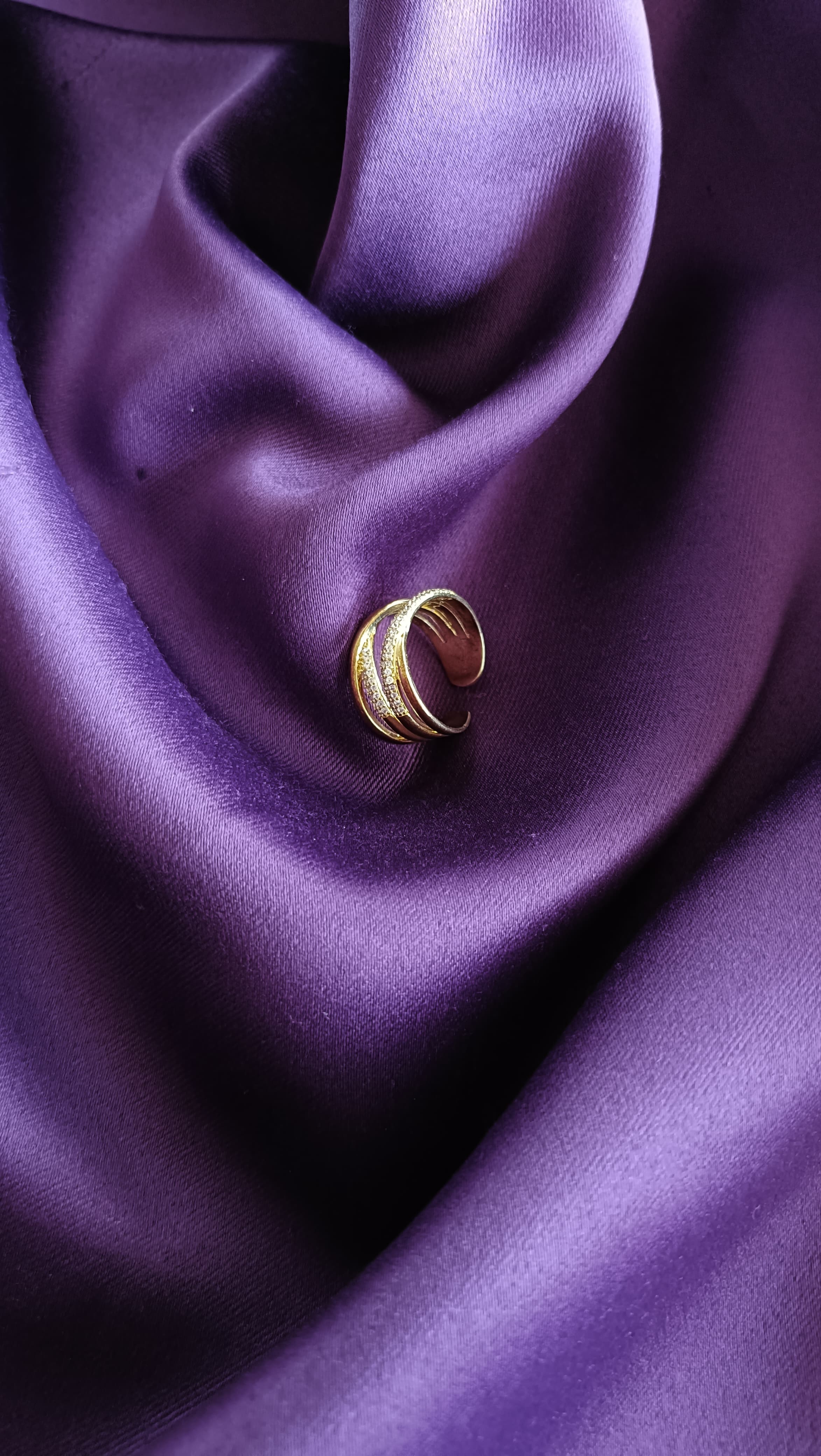 Gold Crossover Pavé Multi-Band Ring flat lay on purple fabric