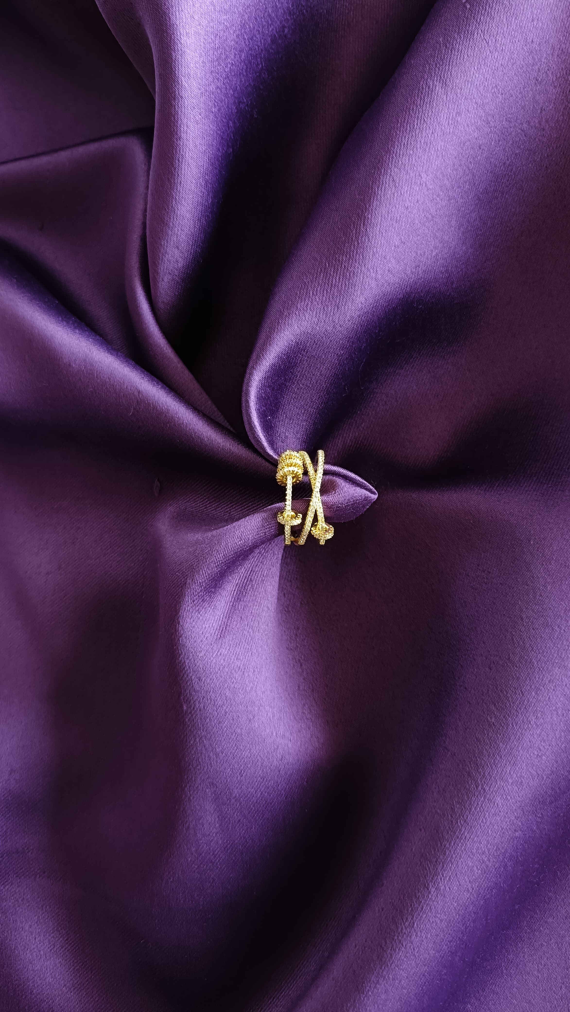 Gold Crystal Knot Double Band Ring flat lay on purple fabric