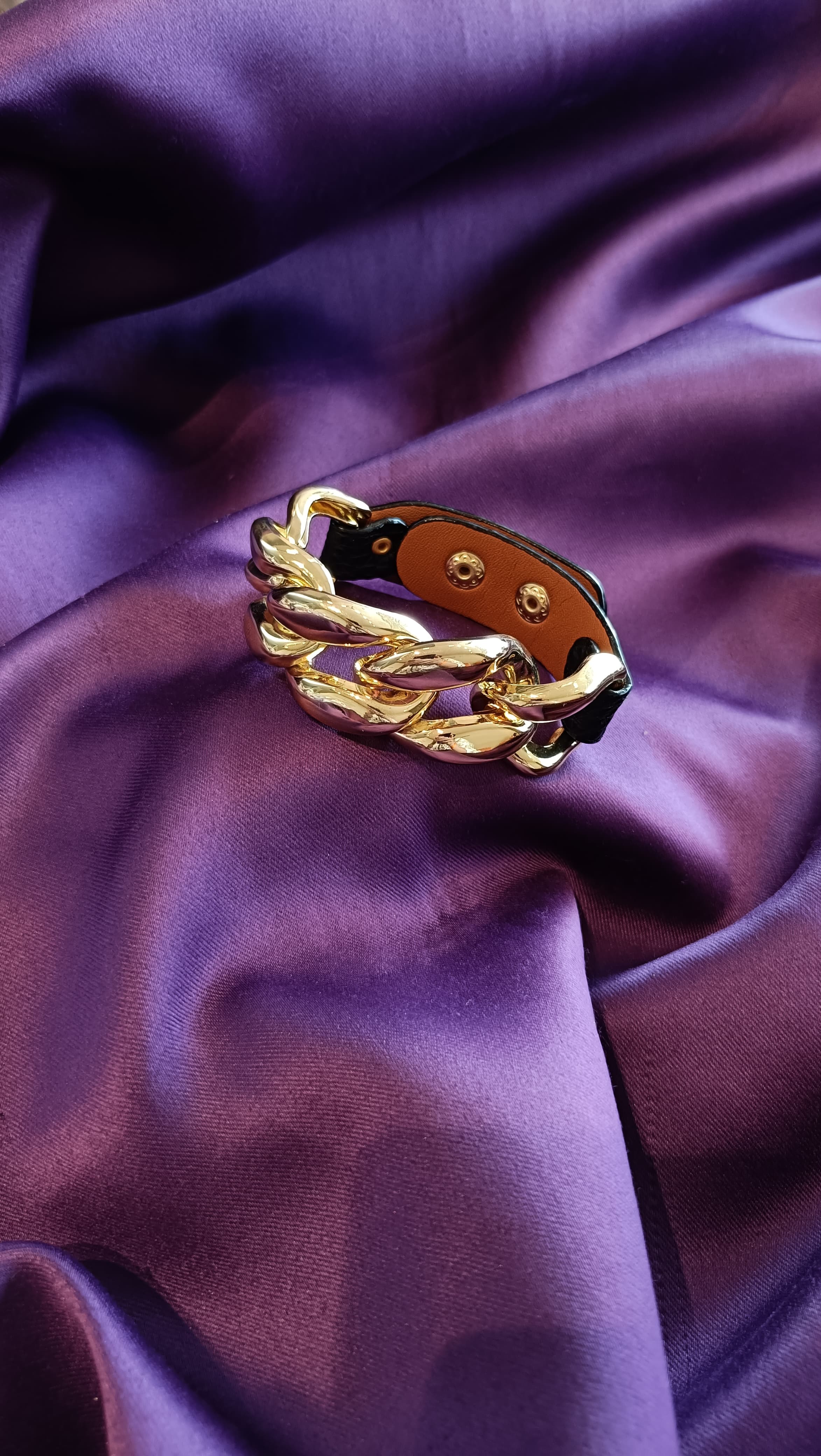 Gold Chunky Curb Chain Black Leather Strap Bracelet coiled flat lay on purple fabric