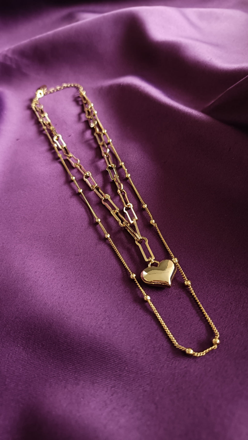 Gold Double-Layer Heart Pendant Necklace Set flat lay on purple fabric