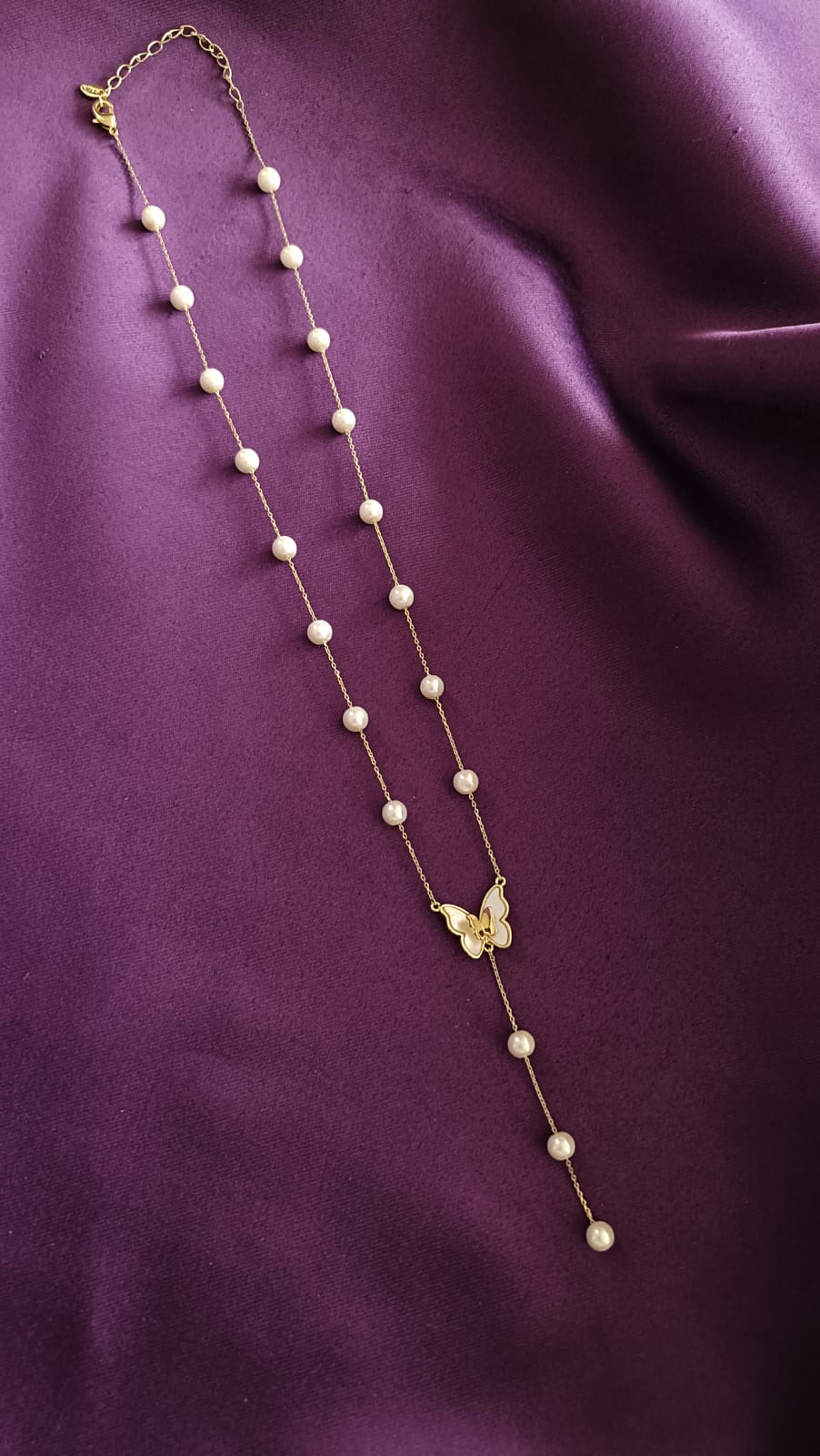 Gold Pearl Station Butterfly Lariat Necklace full length flat lay on purple fabric