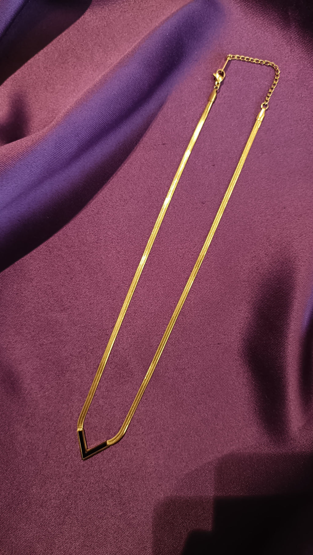 Gold Black Enamel V-Chevron Herringbone Chain Necklace full length flat lay on purple fabric showing lobster clasp and extender
