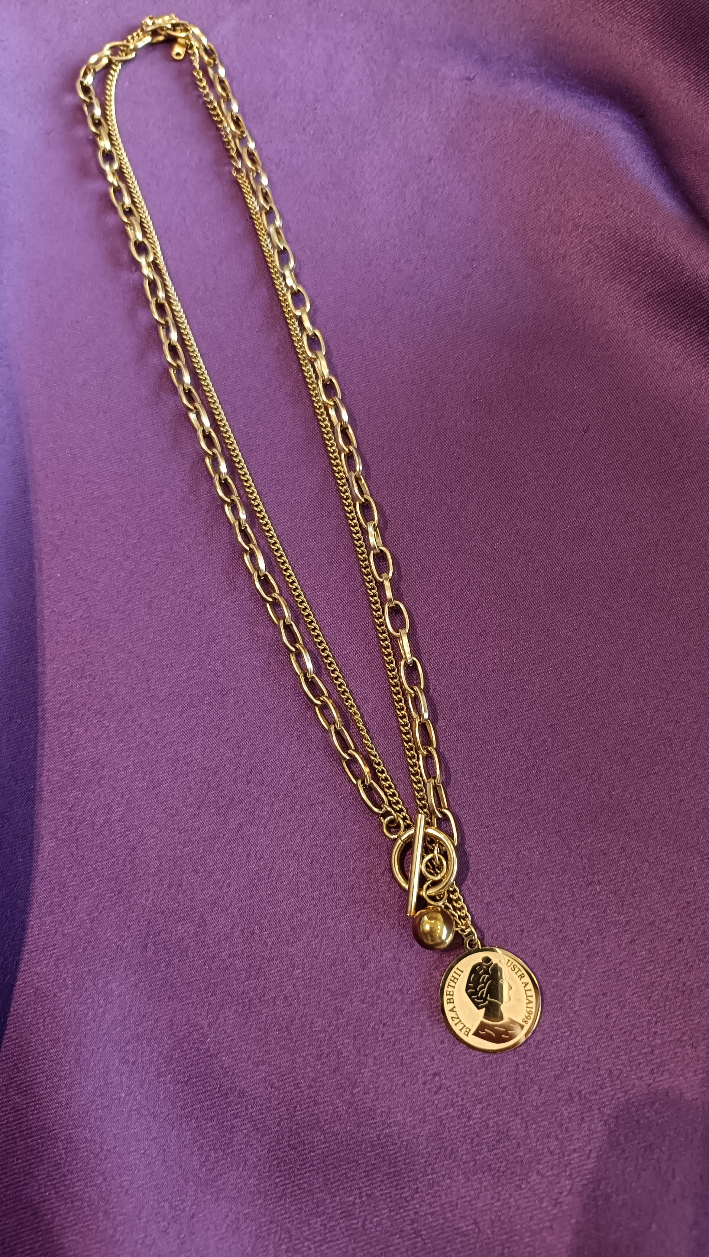 Gold Double-Layer Coin Medallion Necklace flat lay on purple fabric