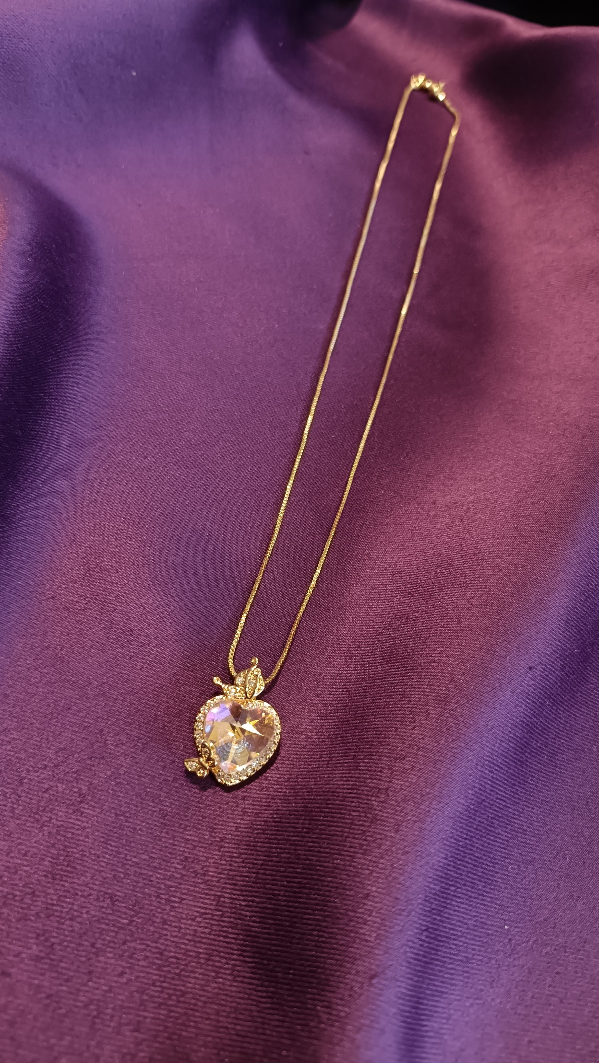 Gold Aurora Heart Crystal Butterfly Necklace close-up flat lay on purple fabric