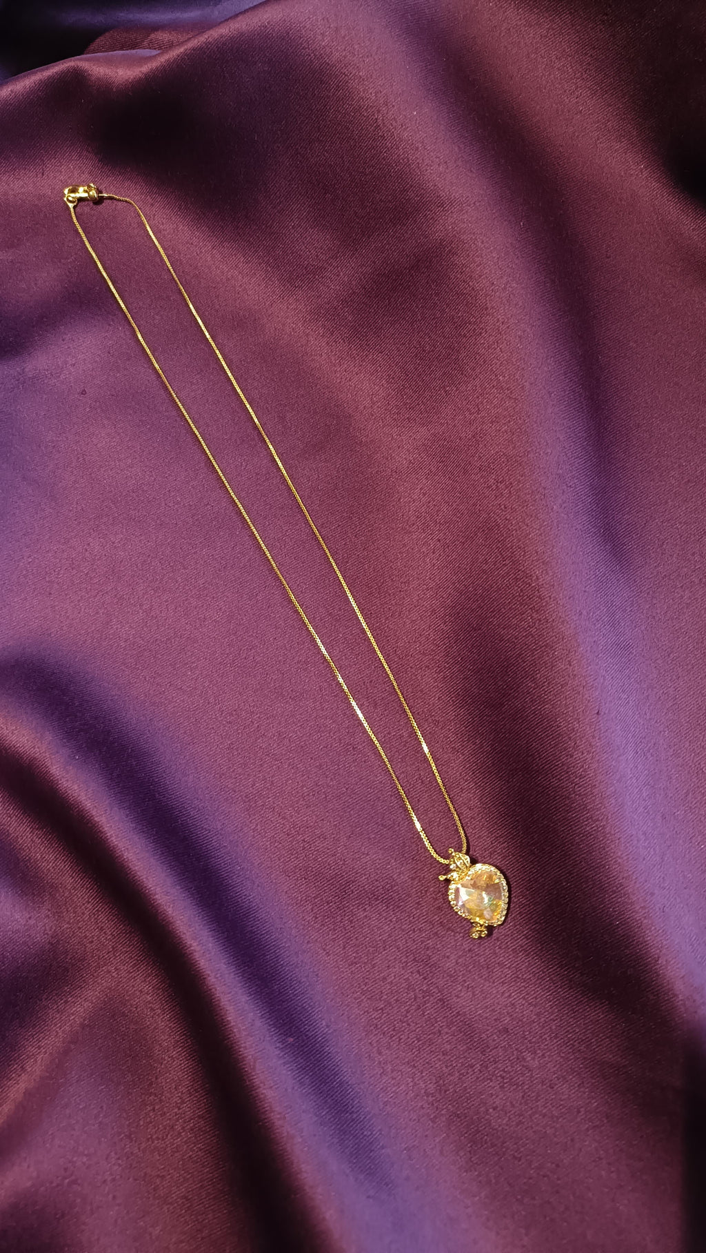 Gold Aurora Heart Crystal Butterfly Necklace flat lay on purple fabric