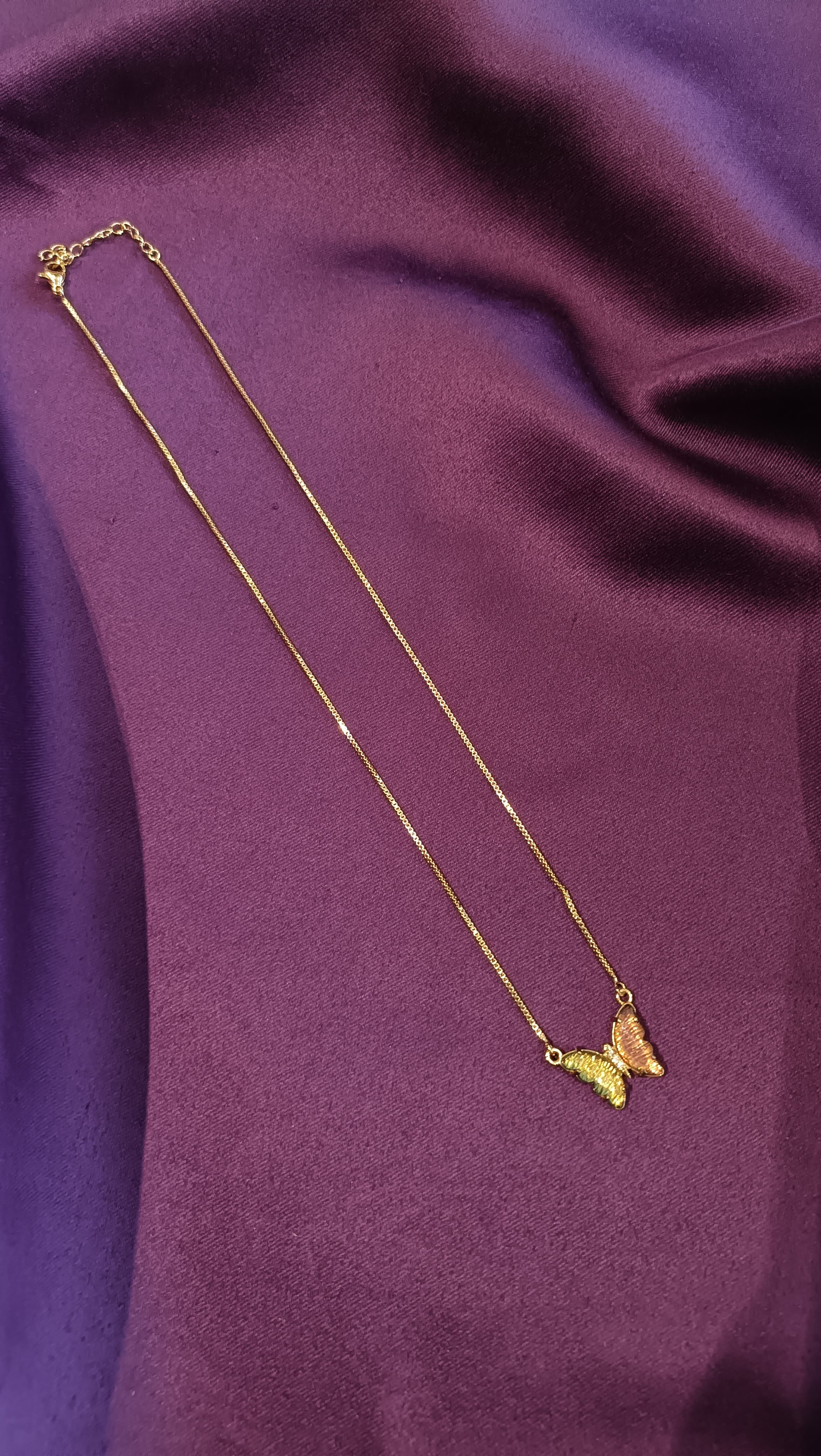 Gold Green Enamel Butterfly Pendant Box Chain Necklace close-up flat lay on purple fabric showing butterfly pendant with enamel wing detail