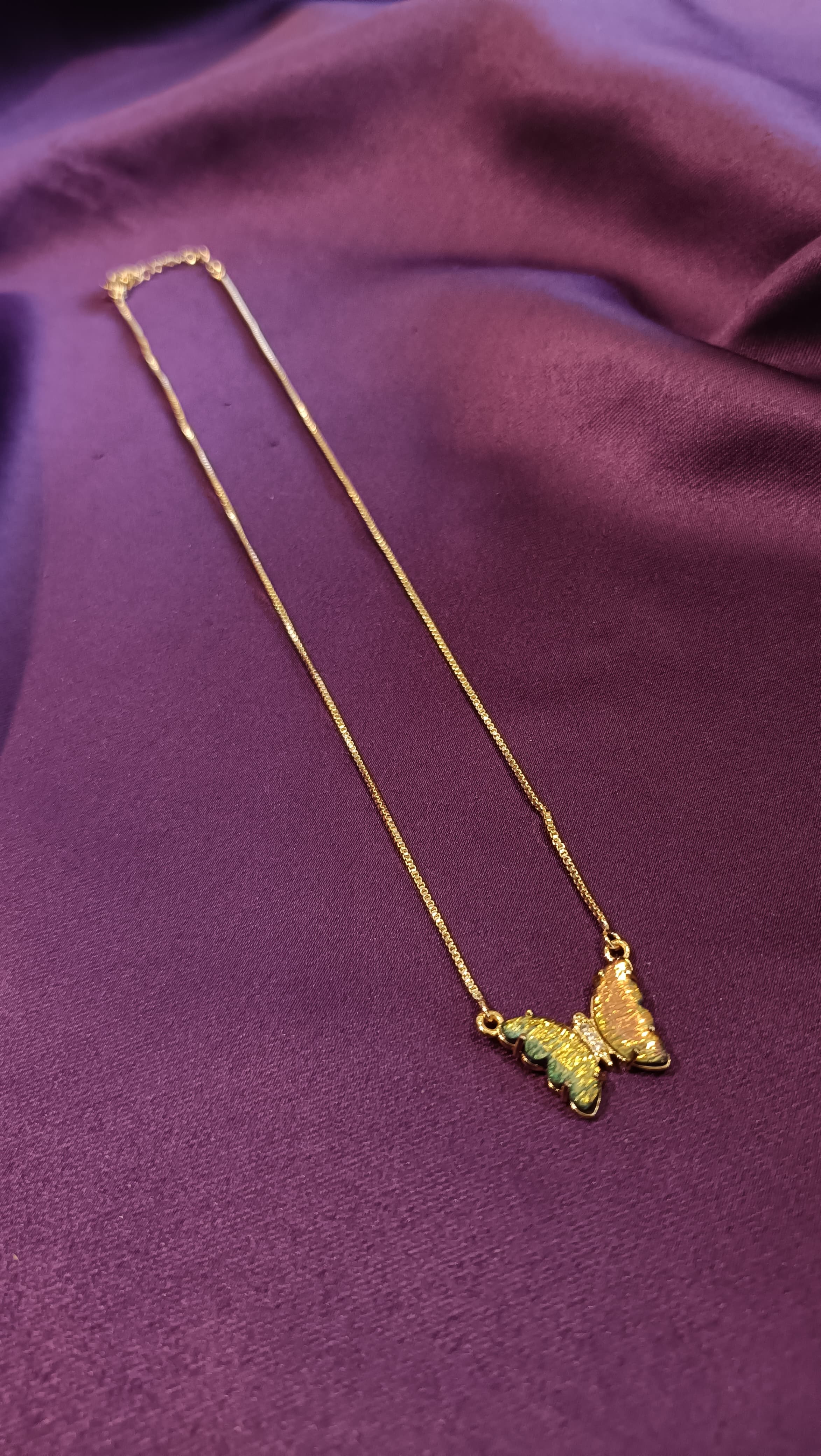 Gold Green Enamel Butterfly Pendant Box Chain Necklace full length flat lay on purple fabric showing lobster clasp and extender
