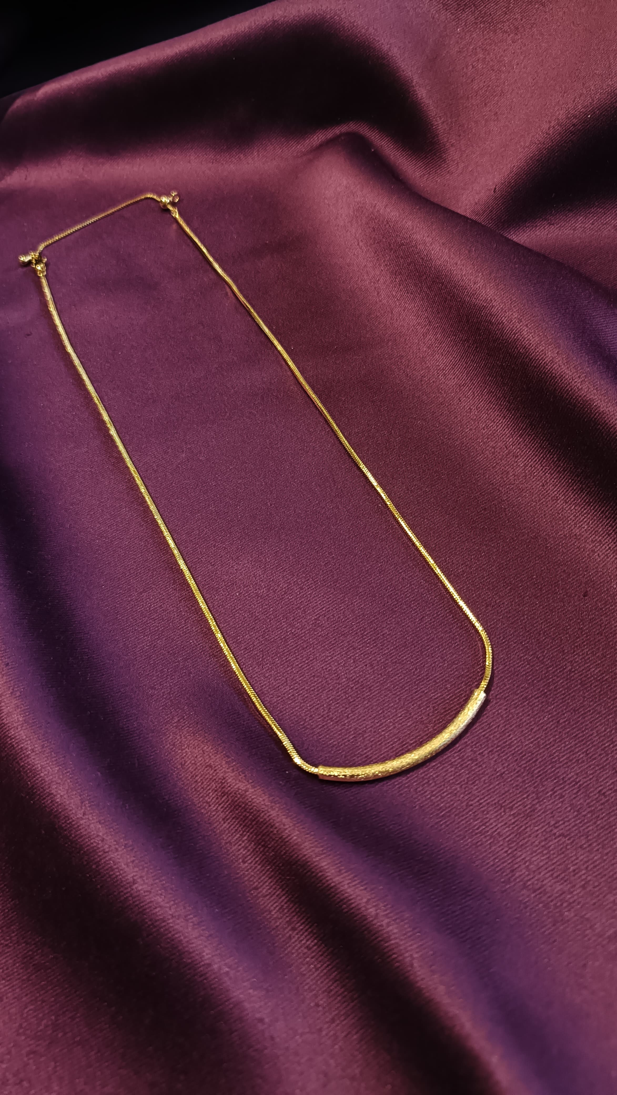 Gold Textured Curved Bar Necklace full length flat lay on purple fabric