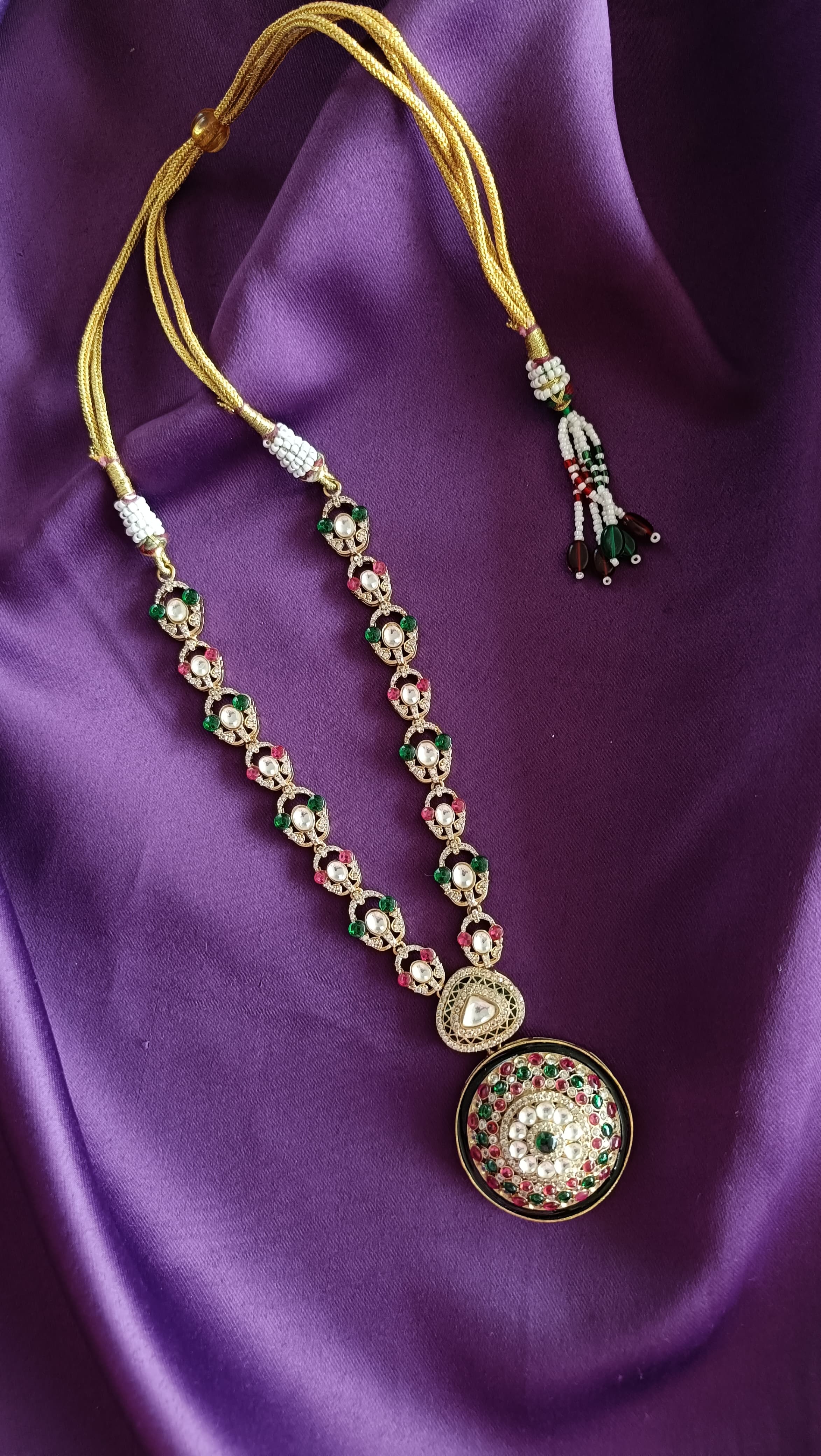 Gold Kundan Polki Ruby & Emerald Earrings pair flat lay on purple fabric