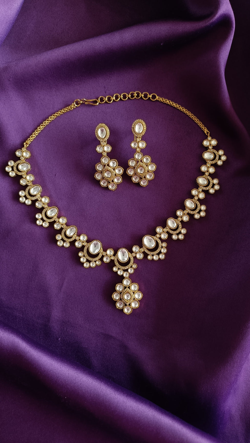 Gold Kundan Polki Floral Cluster Necklace & Drop Earrings Set full flat lay on purple fabric