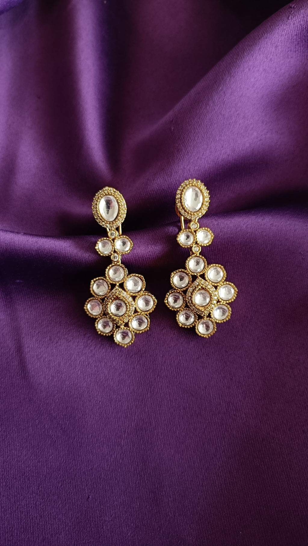 Gold Kundan Polki Floral Cluster Drop Earrings pair flat lay on purple fabric