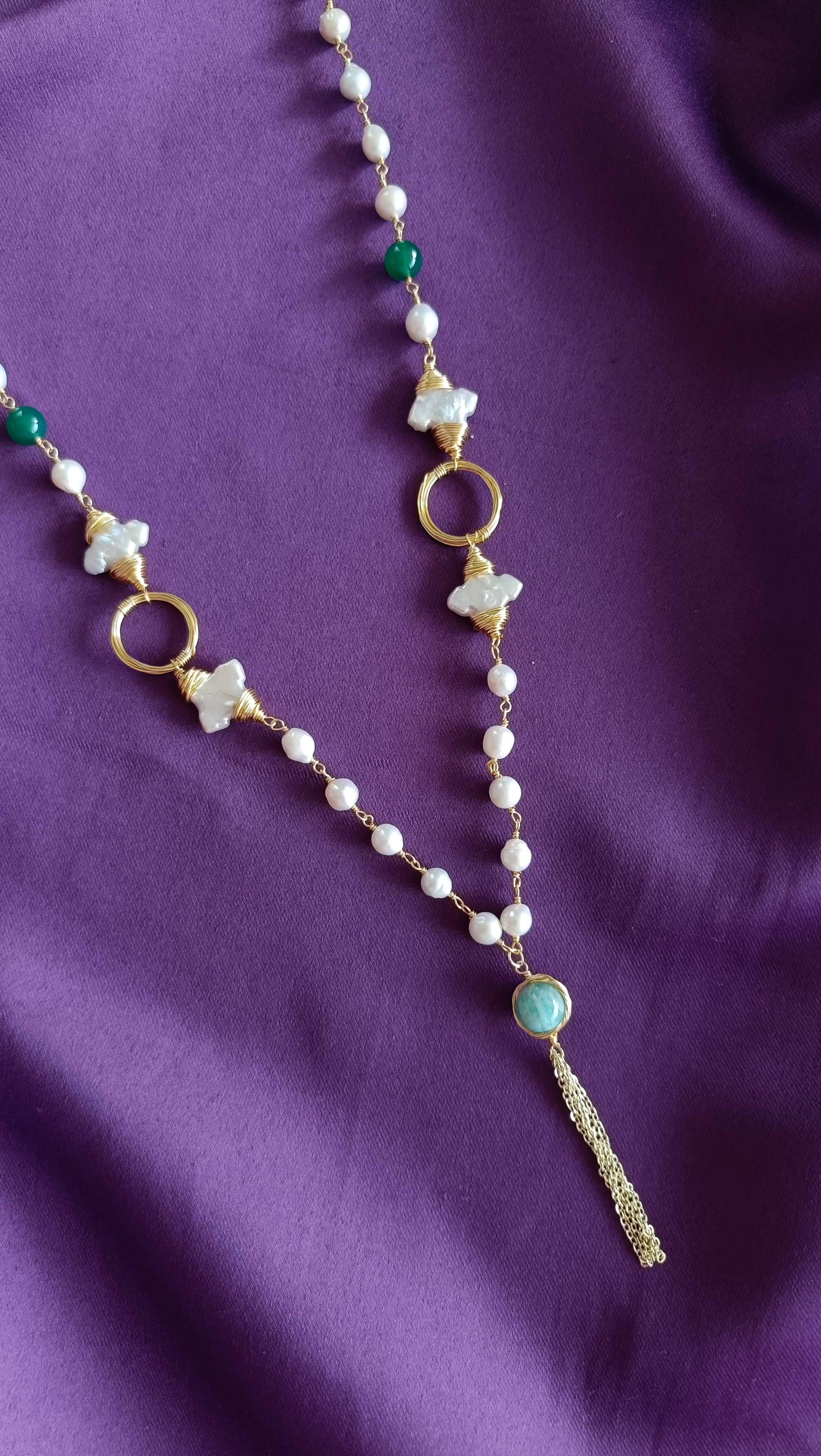 Gold Wire-Wrapped Mother-of-Pearl Flower & Green Onyx Long Lariat Necklace centre detail flat lay on purple fabric showing MOP flowers, open rings and chalcedony tassel