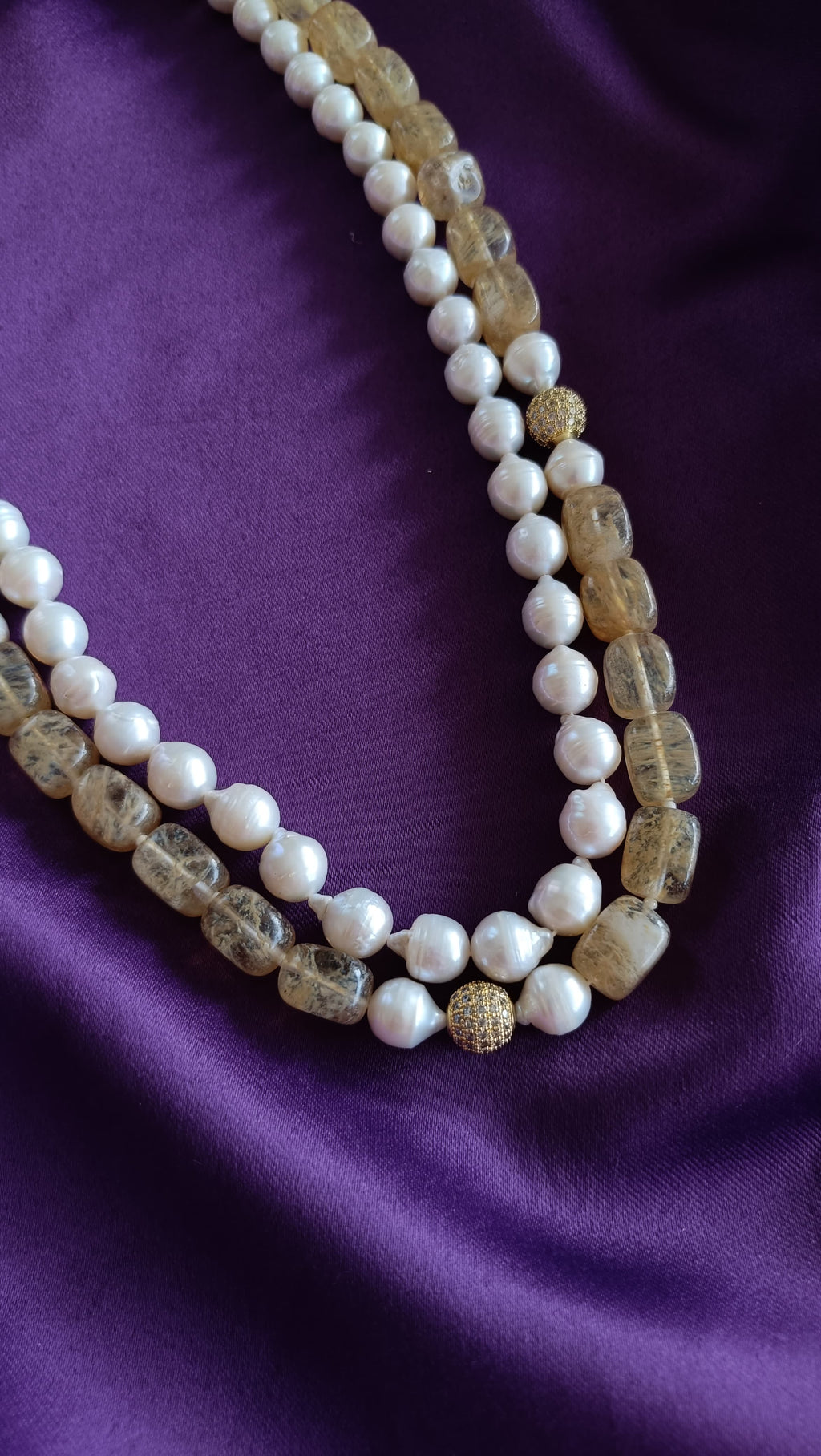 Gold Double-Strand Freshwater Pearl & Rutilated Quartz Necklace centre detail close-up flat lay on purple fabric showing pavé ball stations