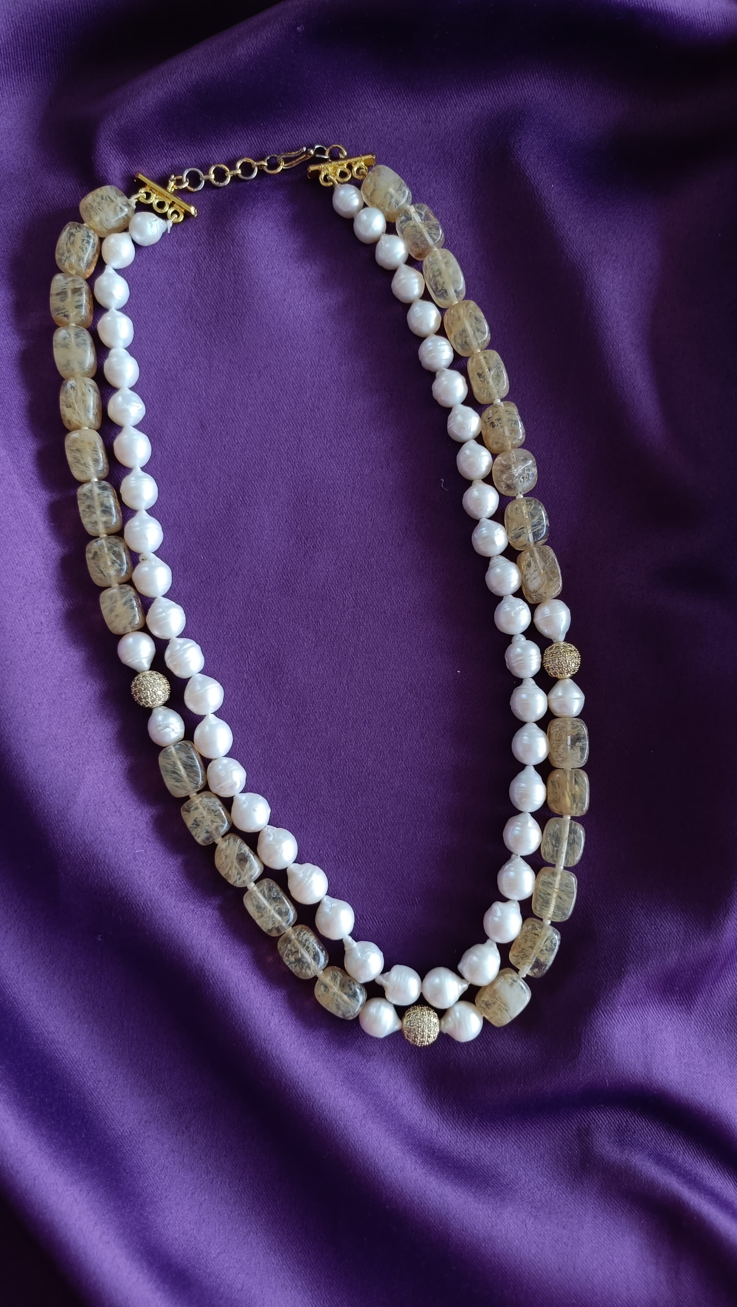 Gold Double-Strand Freshwater Pearl & Rutilated Quartz Necklace full flat lay on purple fabric showing toggle clasp