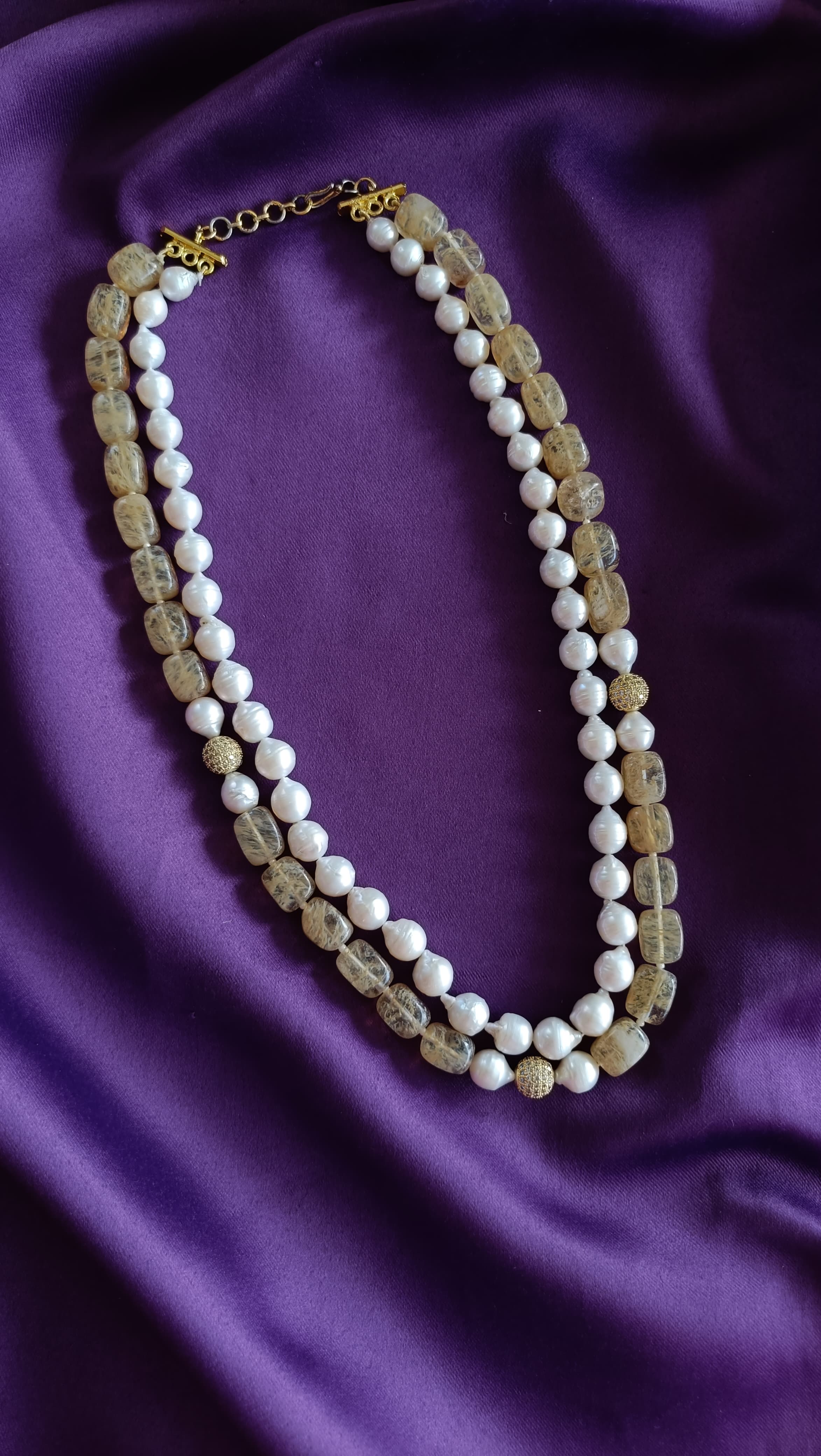 Gold Double-Strand Freshwater Pearl & Rutilated Quartz Necklace full length flat lay on purple fabric showing both strands and toggle clasp extender