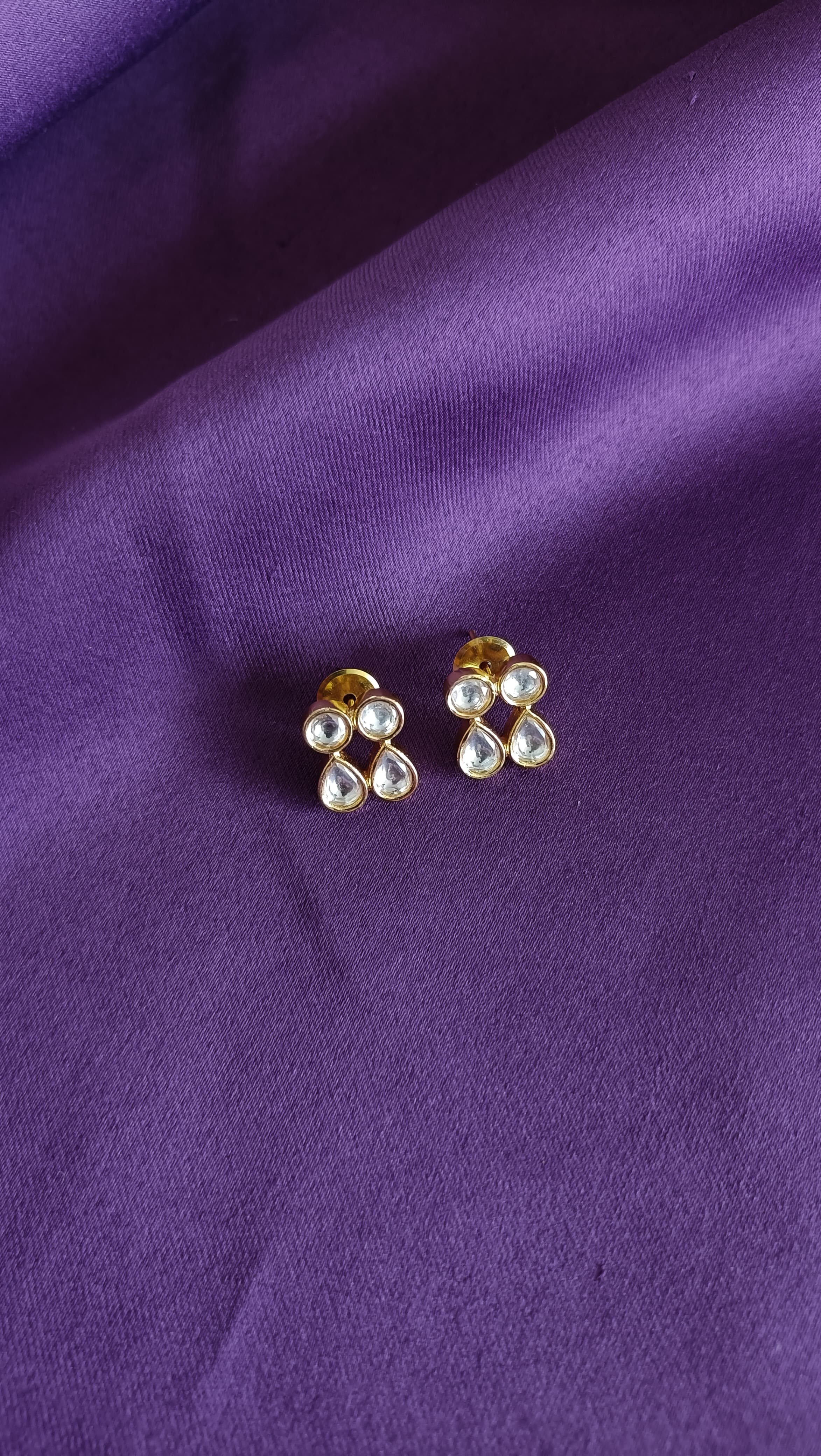 Gold Kundan Polki Stud Earrings pair flat lay on purple fabric