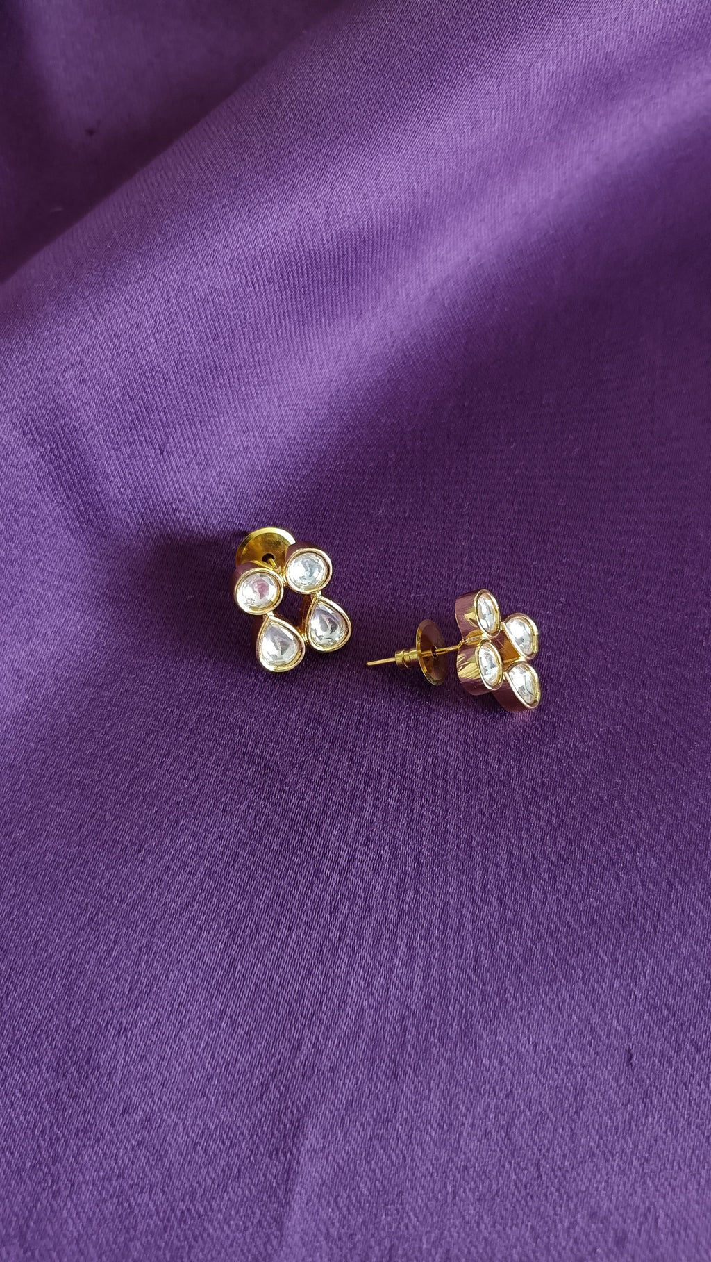 Gold Kundan Polki Stud Earrings pair close-up flat lay on purple fabric