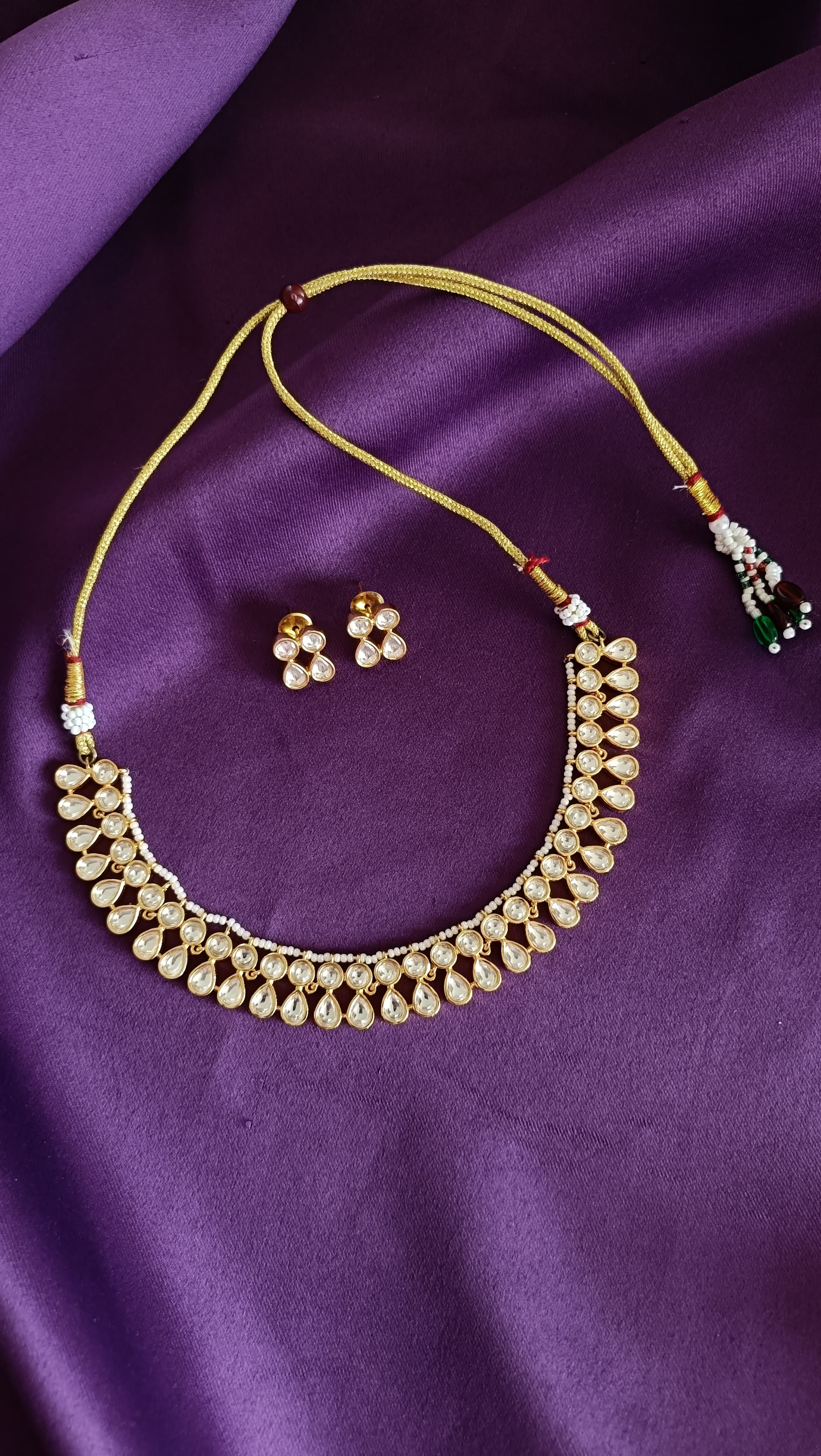 Gold Kundan Polki Pear-Drop Choker & Stud Earrings Set full flat lay on purple fabric with dori closure