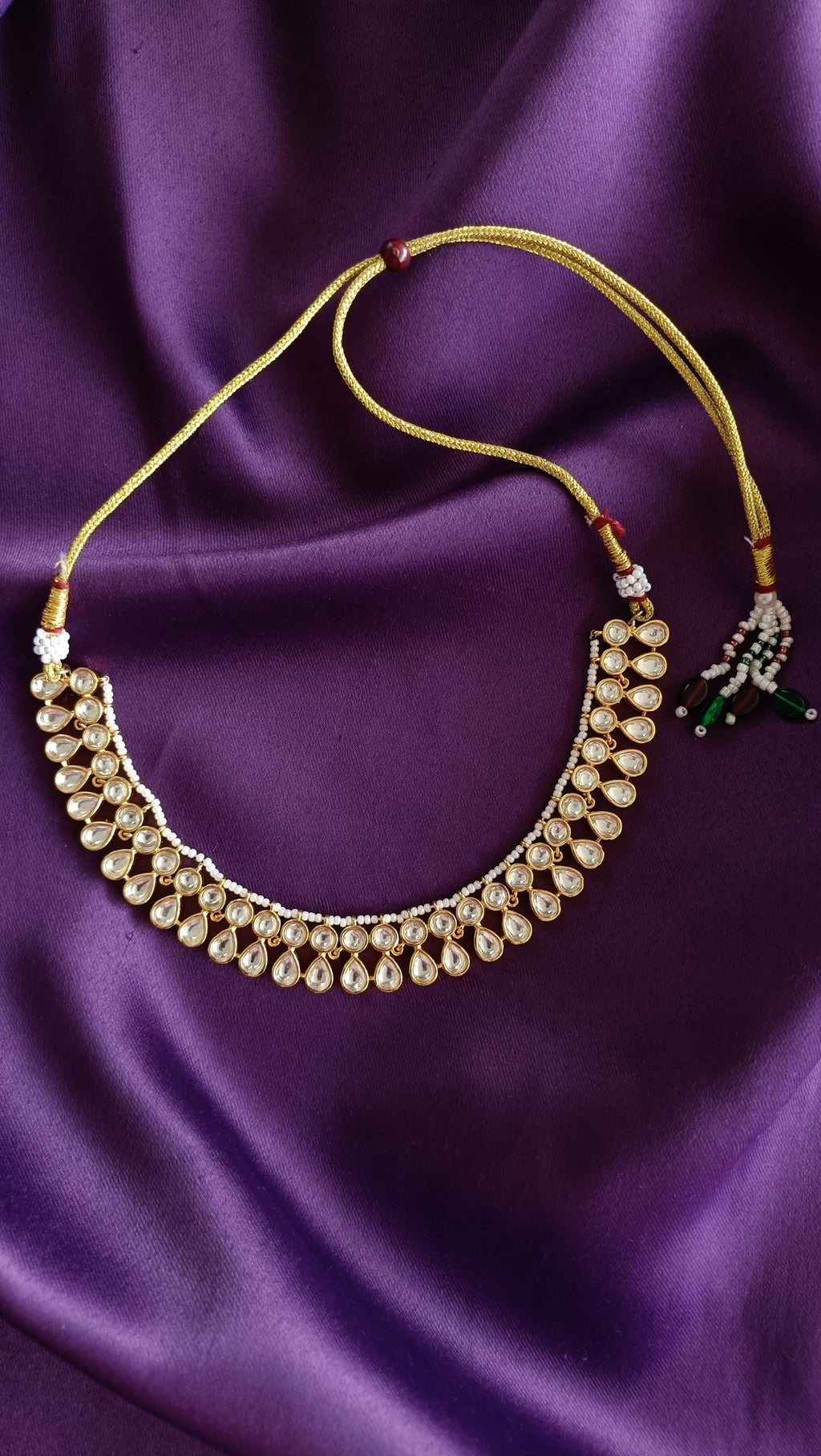 Gold Kundan Polki Pear-Drop Choker necklace close-up flat lay on purple fabric
