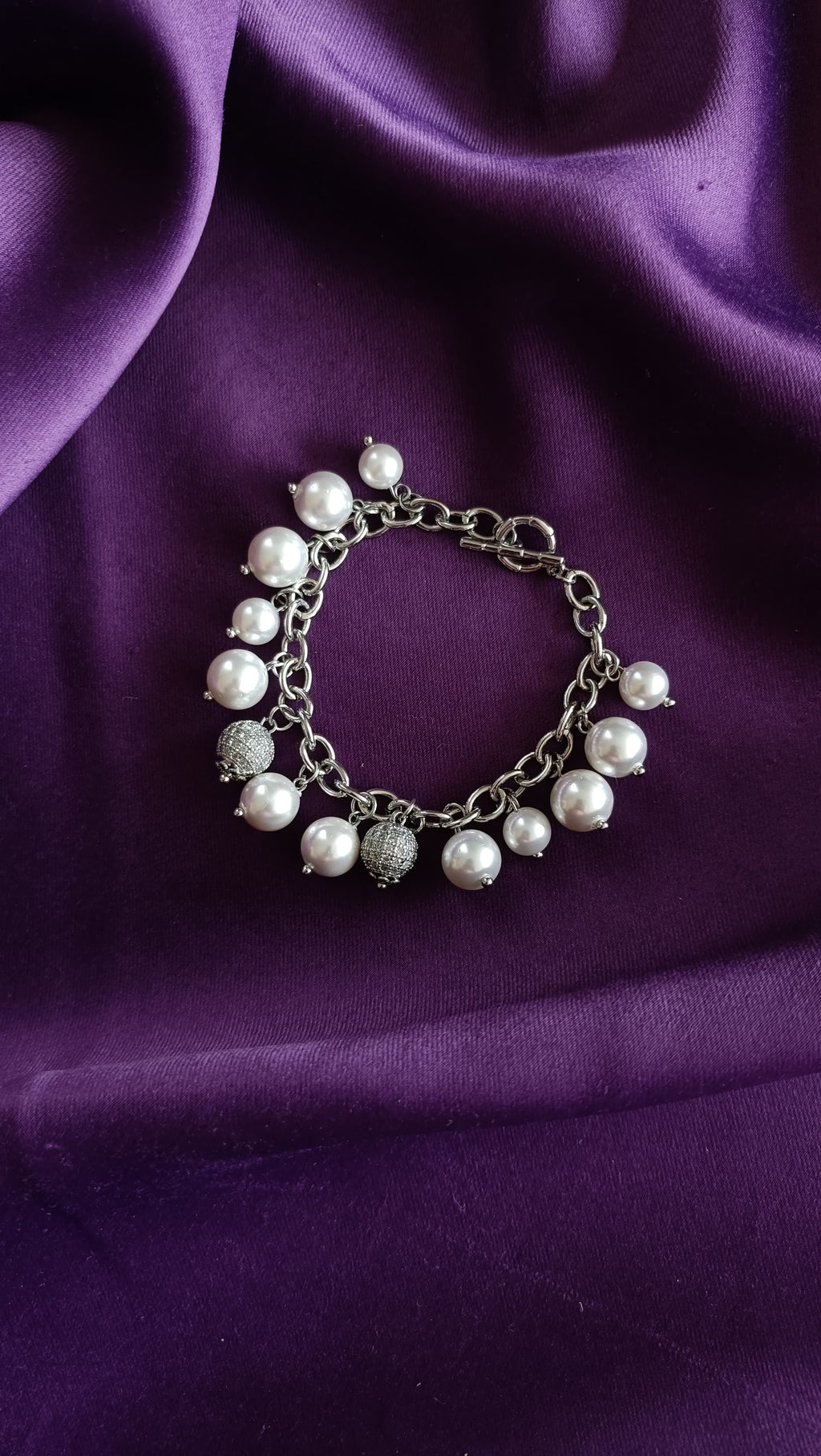 Silver Pearl & Pavé Ball Charm Bracelet flat lay on purple fabric showing toggle clasp and charm fringe