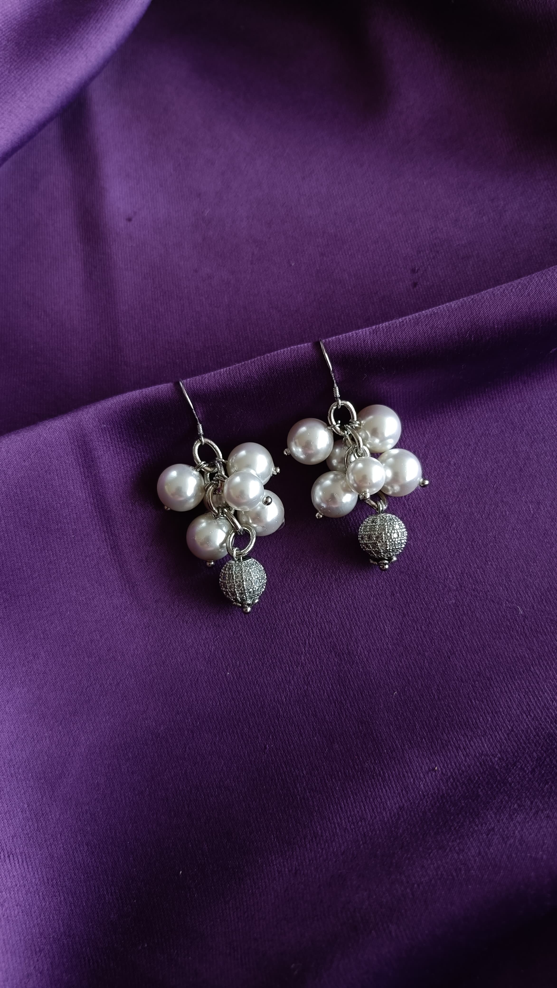 Silver Five-Pearl Cluster Drop Earrings with Pavé Ball Drop pair flat lay on purple fabric