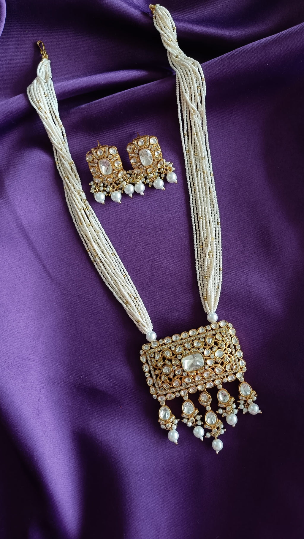 Gold Kundan Polki Rectangular Pendant close-up flat lay on purple fabric showing polki encrustation and pearl drops