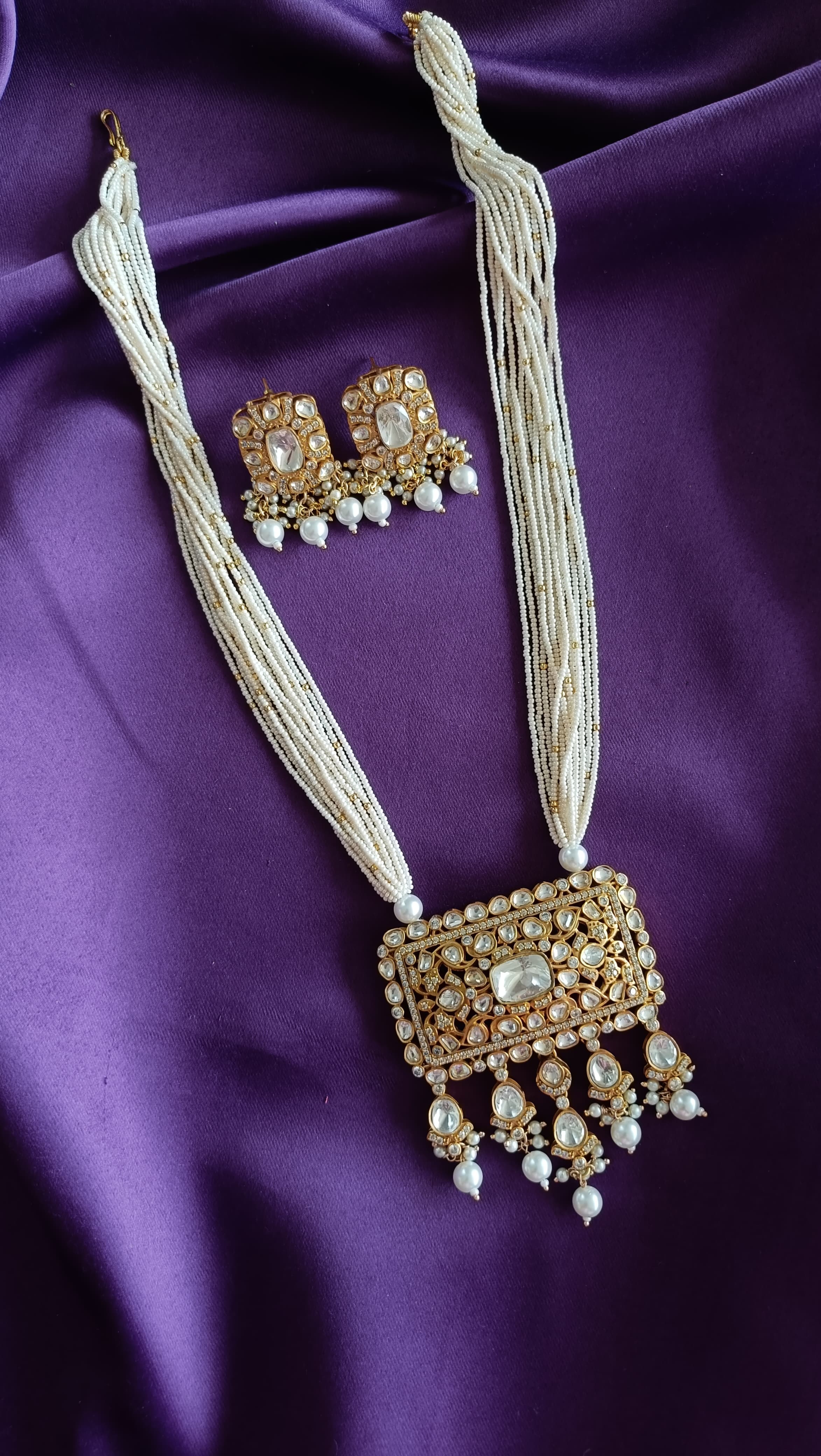 Gold Kundan Polki Rectangular Pendant close-up flat lay on purple fabric showing polki encrustation and pearl drops
