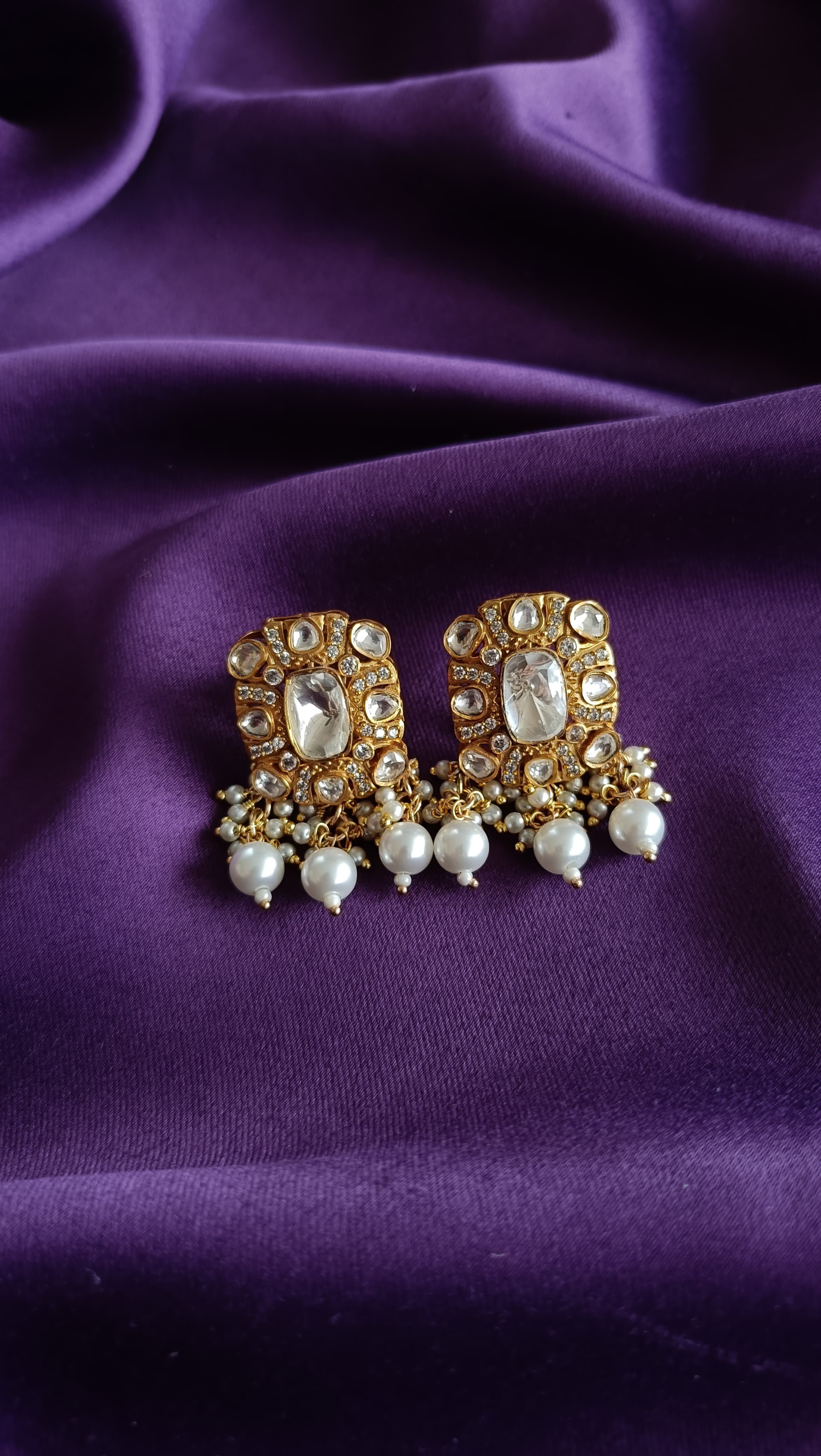 Gold Kundan Polki Rectangular Stud Earrings with Pearl Drops front view flat lay on purple fabric