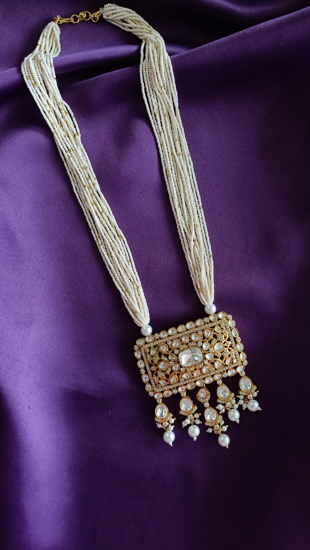 Gold Kundan Polki Rectangular Pendant Multi-Strand Seed Pearl Necklace full length flat lay on purple fabric showing clasp