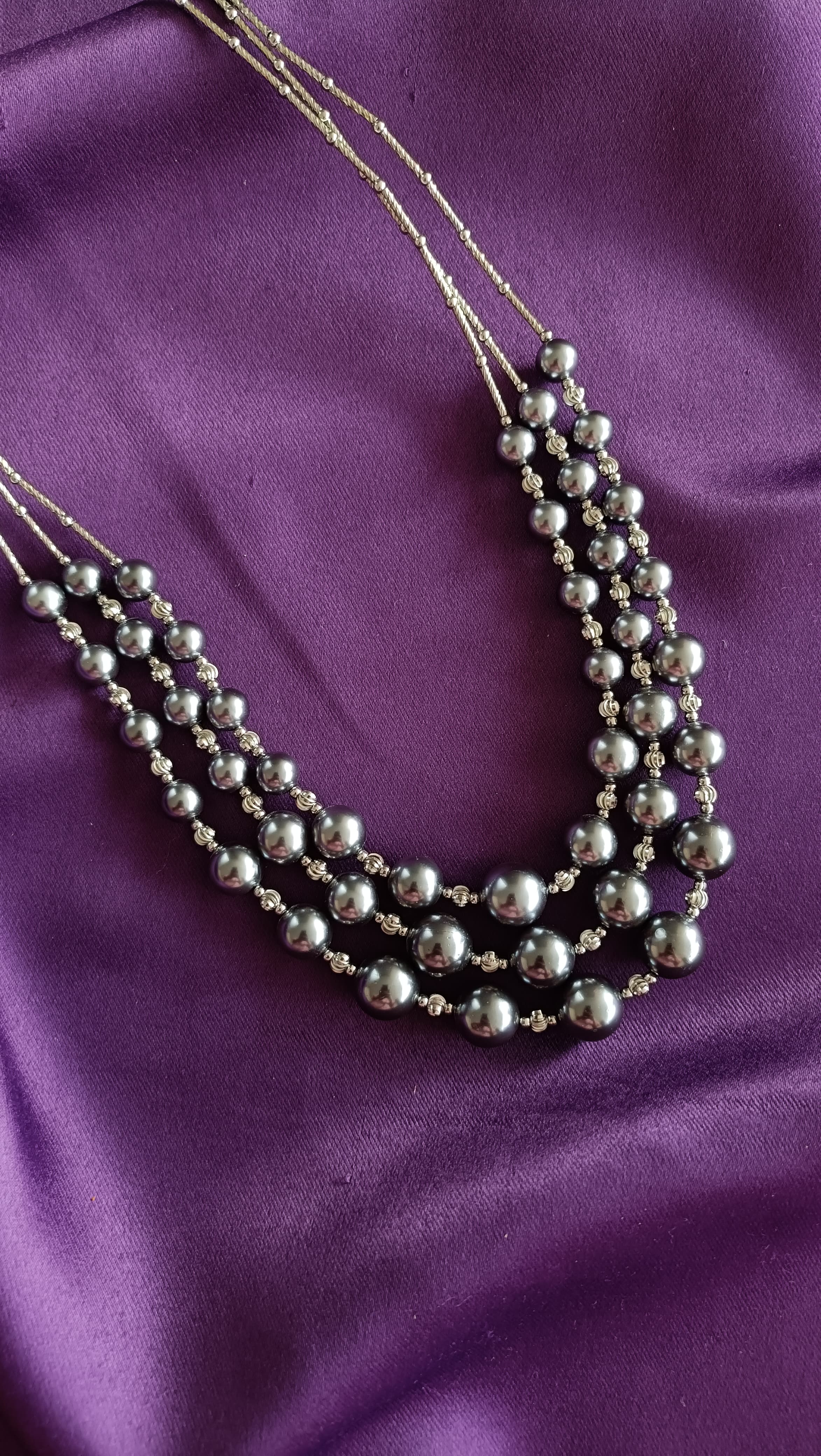 Silver Four-Strand Graduated Grey Pearl & Rondelle Spacer Necklace centre detail flat lay on purple fabric
