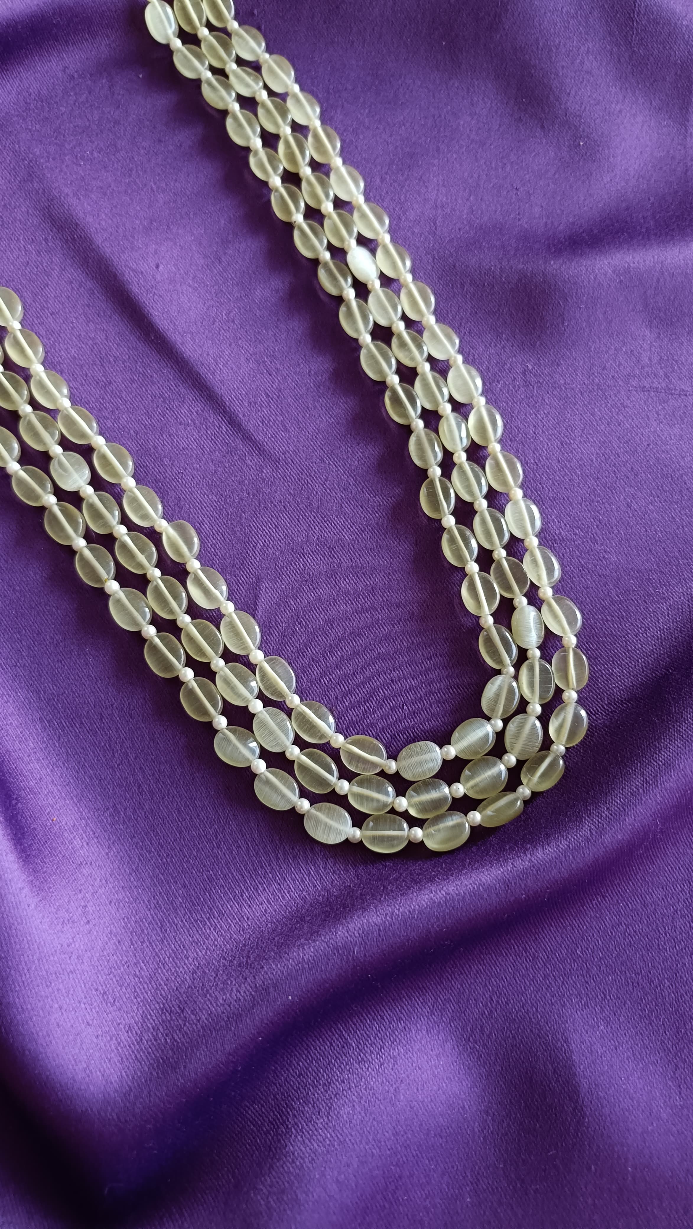 Triple-Strand Prehnite Green Tumbled Bead Necklace close-up flat lay on purple fabric