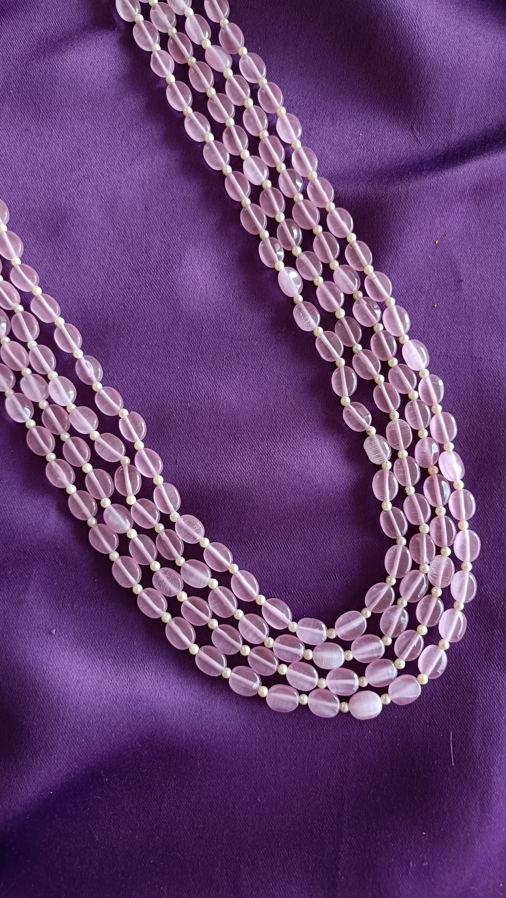 Quadruple-Strand Rose Quartz Tumbled Bead Necklace close-up flat lay on purple fabric