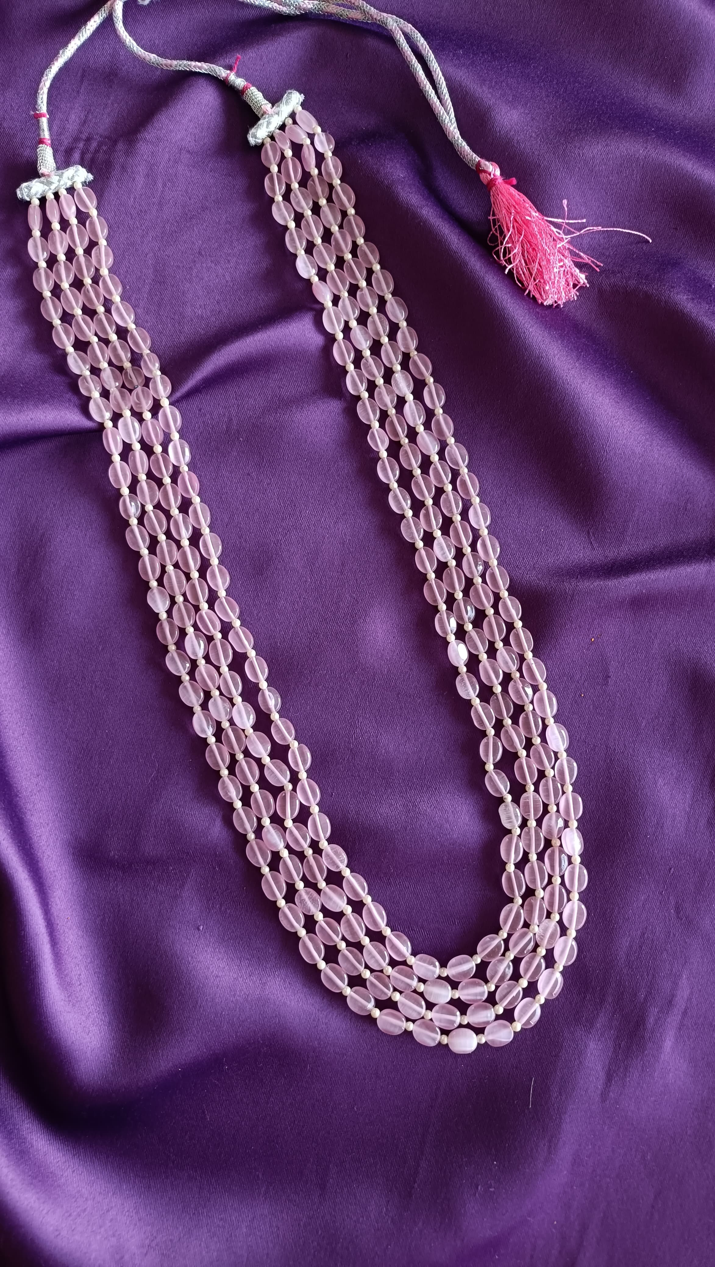 Quadruple-Strand Rose Quartz Tumbled Bead Necklace full length flat lay on purple fabric with dori closure