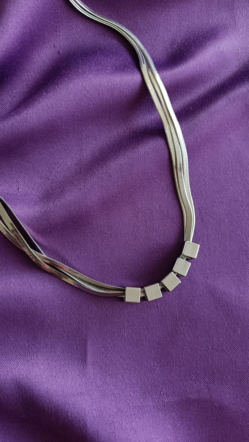 Silver Multi-Strand Herringbone Chain Necklace with Cube Bead Accents detail flat lay on purple fabric