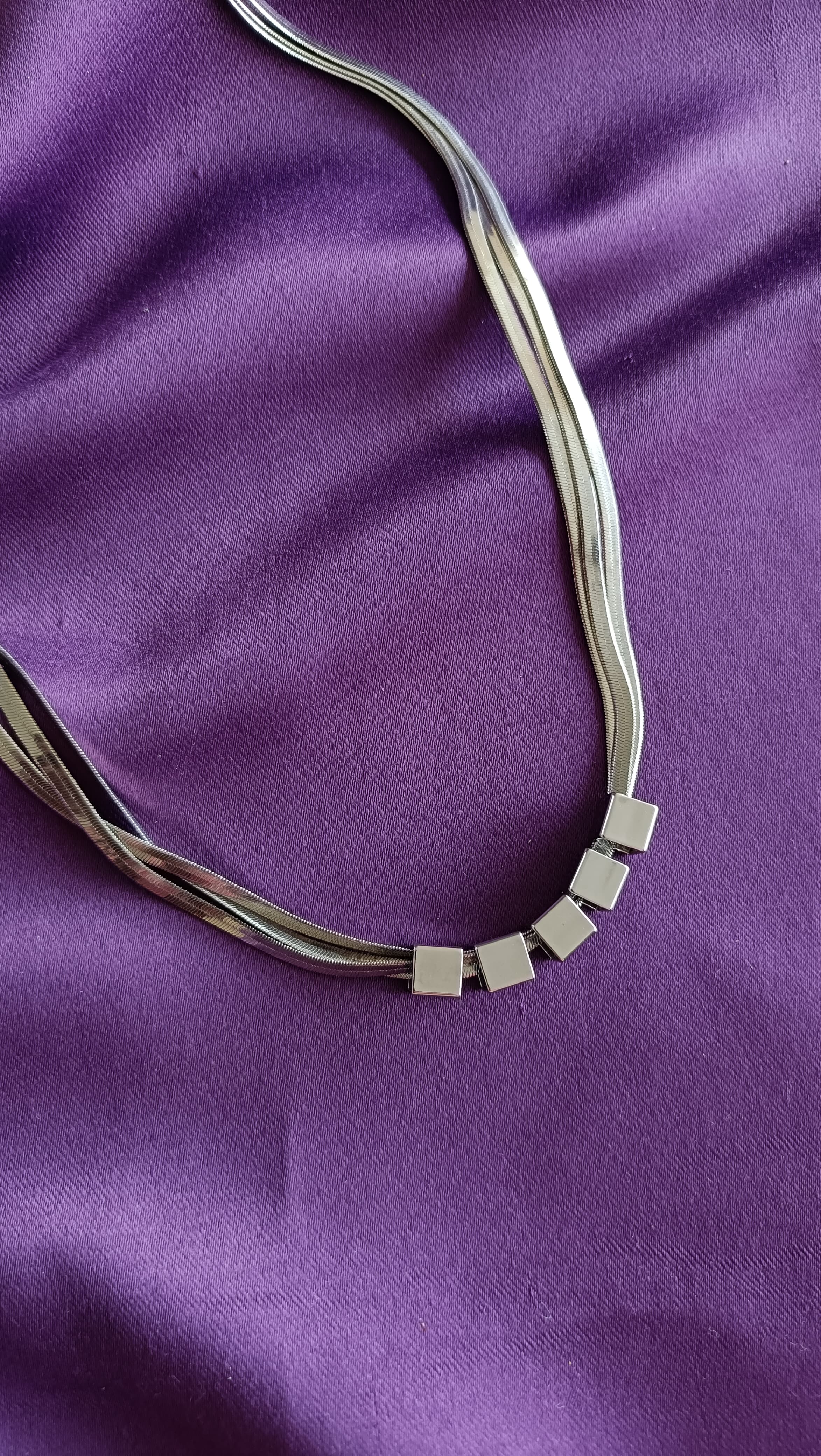 Silver Multi-Strand Herringbone Chain Necklace with Cube Bead Accents detail flat lay on purple fabric