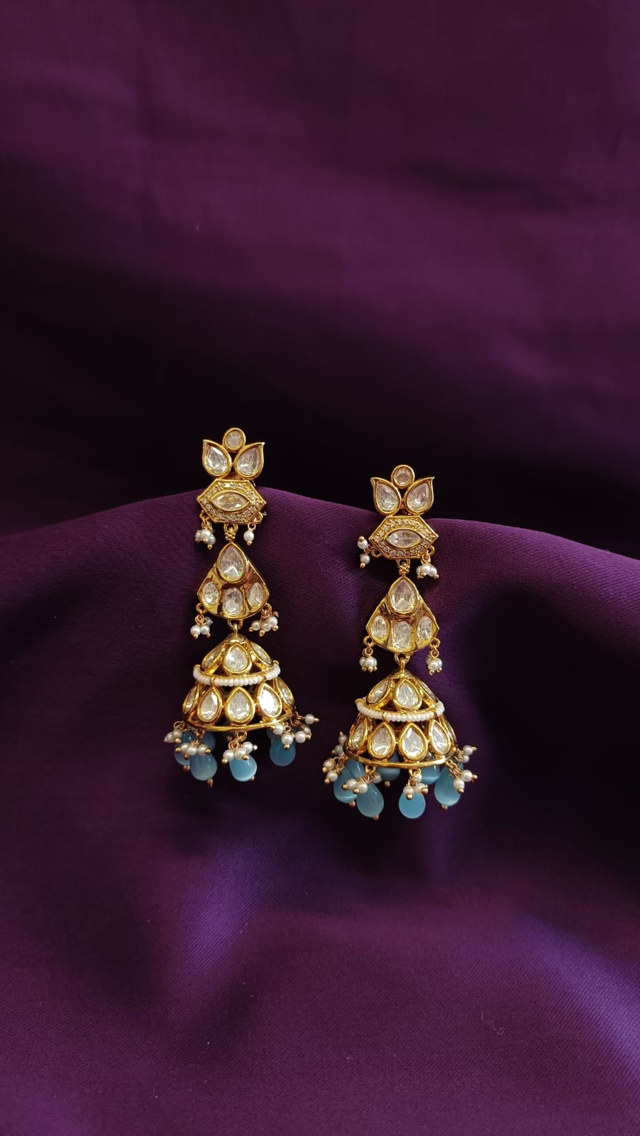 Gold Kundan Polki Three-Tier Jhumka Earrings pair flat lay on purple fabric