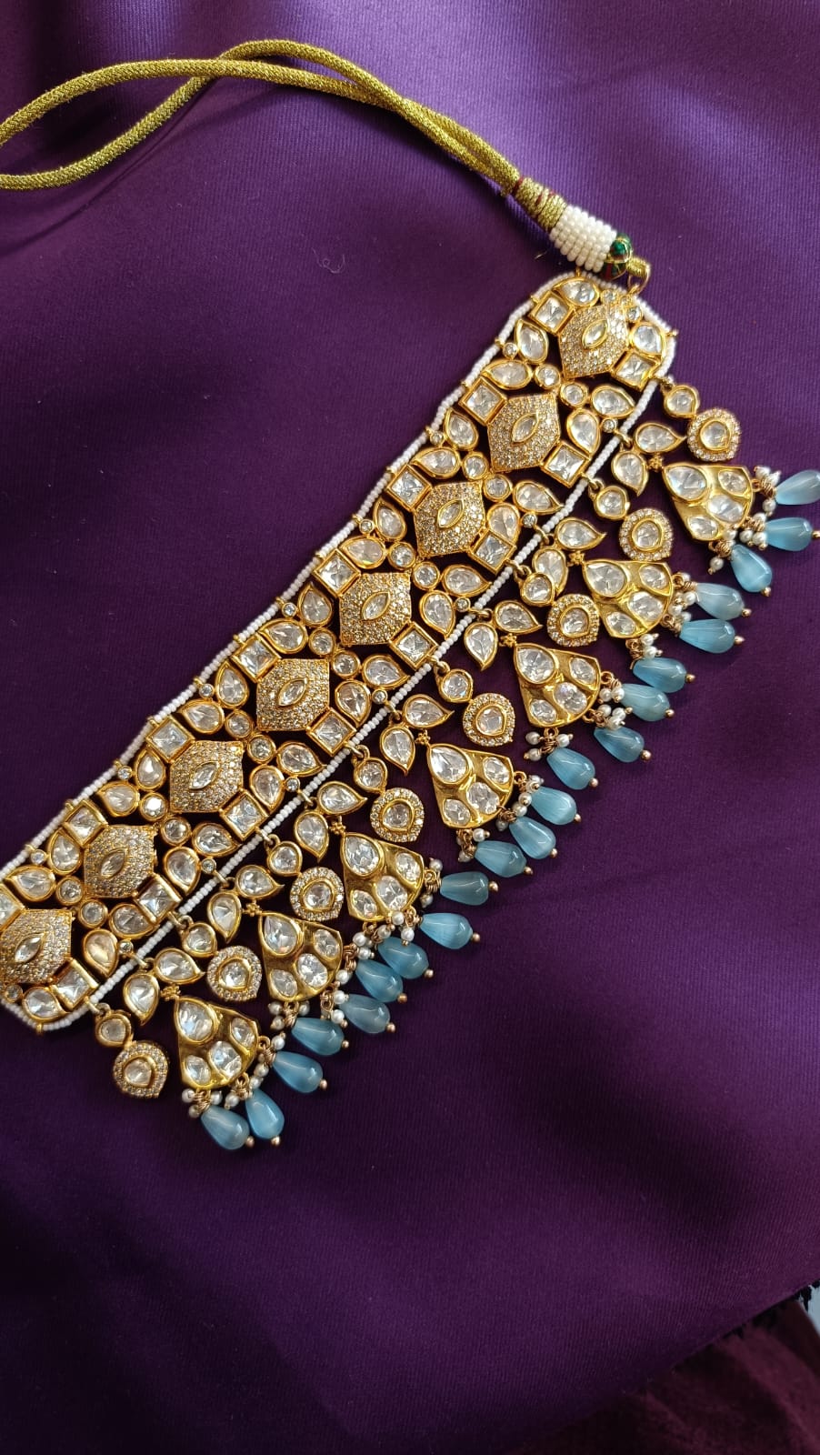 Gold Kundan Polki Wide Choker necklace close-up flat lay on purple fabric showing polki encrustation and aqua chalcedony fringe drops