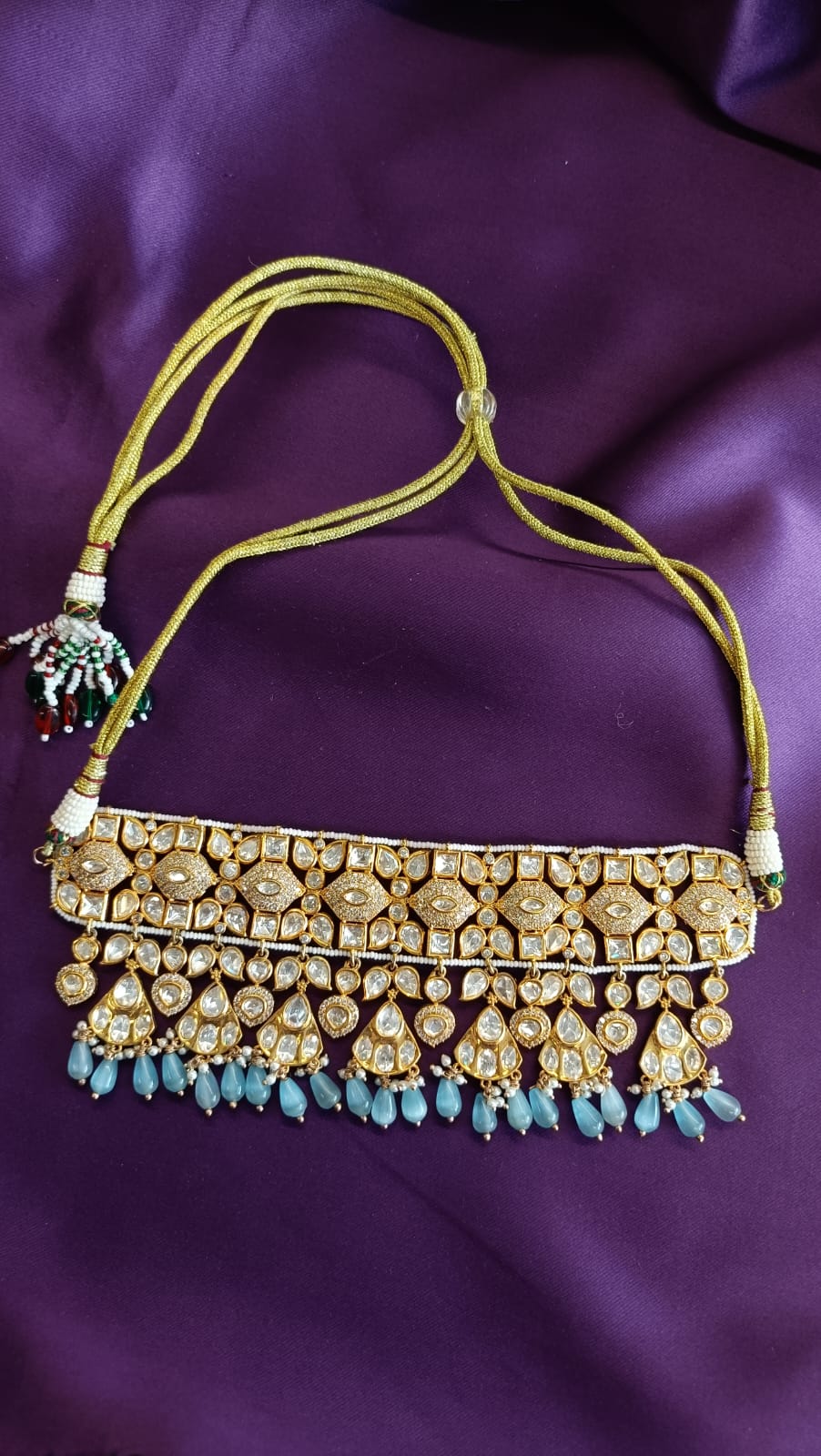 Gold Kundan Polki Wide Choker necklace full length flat lay on purple fabric showing dori cord, seed pearl border and gold tassel closure
