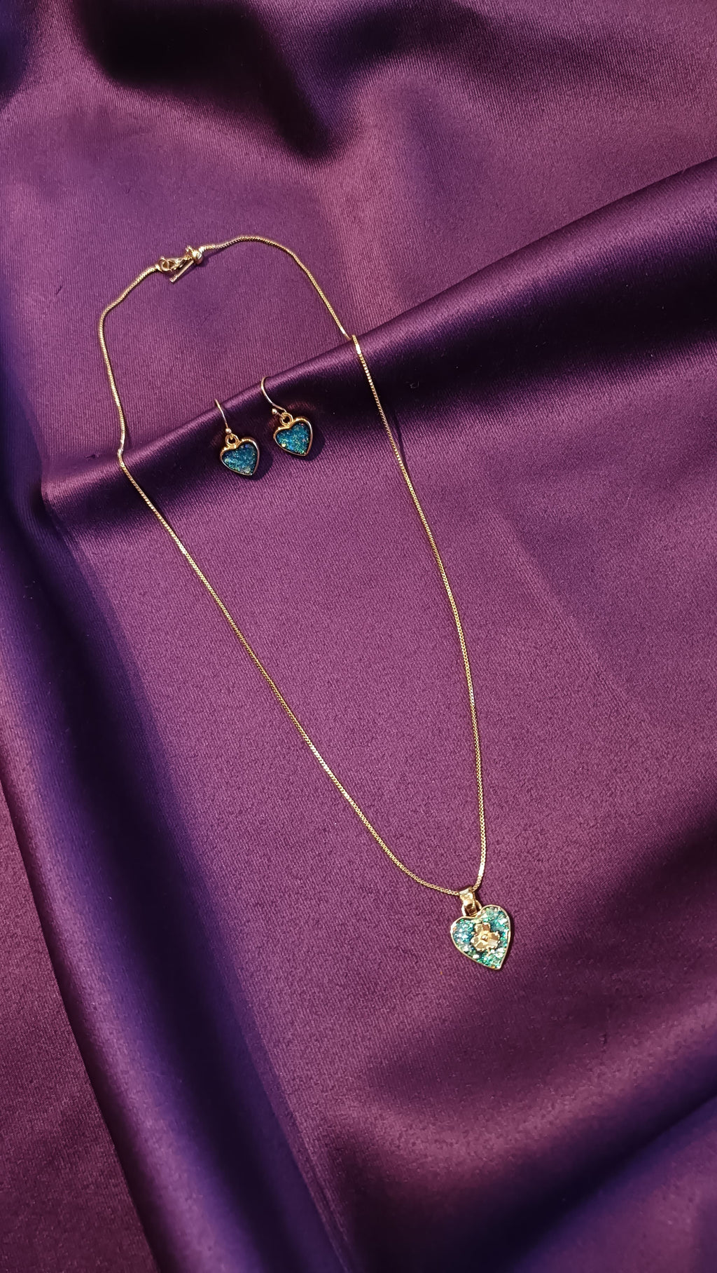 Gold Emerald Pavé Heart Pendant Box Chain Necklace & Drop Earrings Set full flat lay on purple fabric showing lobster clasp and earrings